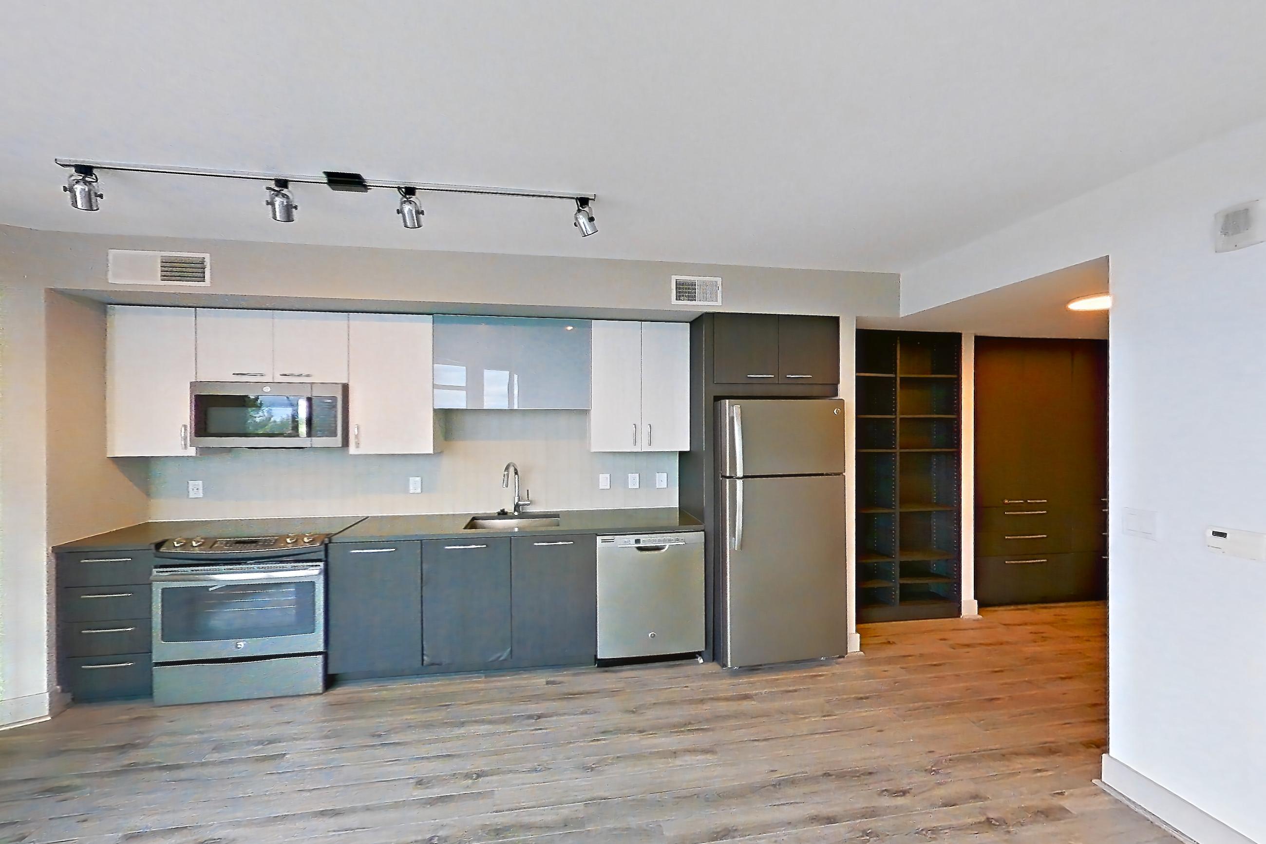 Living space with dark countertops, dishwasher, electric range, light wood-finish flooring, oven/range, refrigerator, and stainless steel appliances, Apartment 902 at Adaire