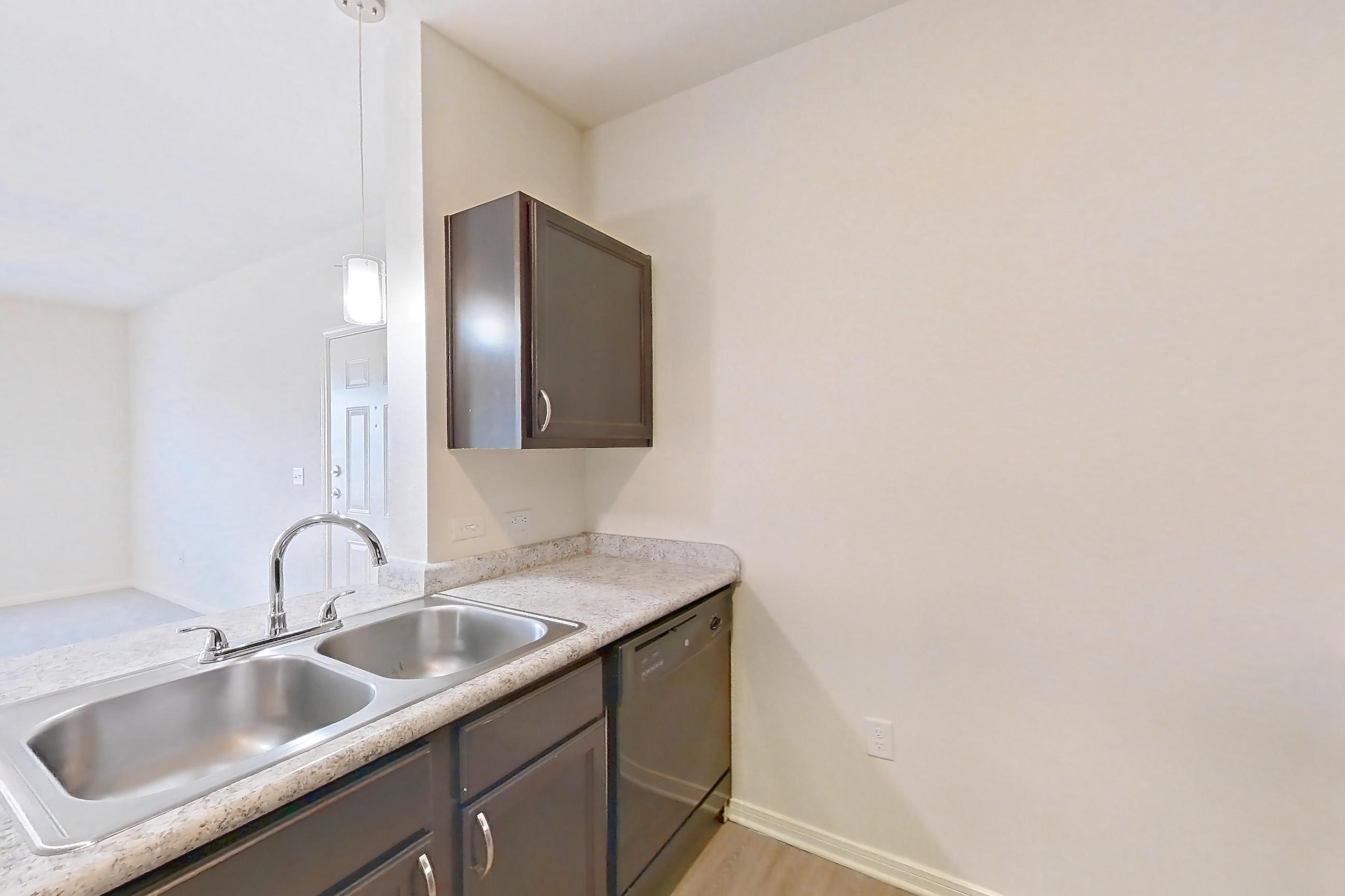Kitchen with black appliances, dishwasher, electric range, light countertops, light stone countertops, light wood-finish flooring, oven/range, and refrigerator, Apartment 323 at Tuckaway