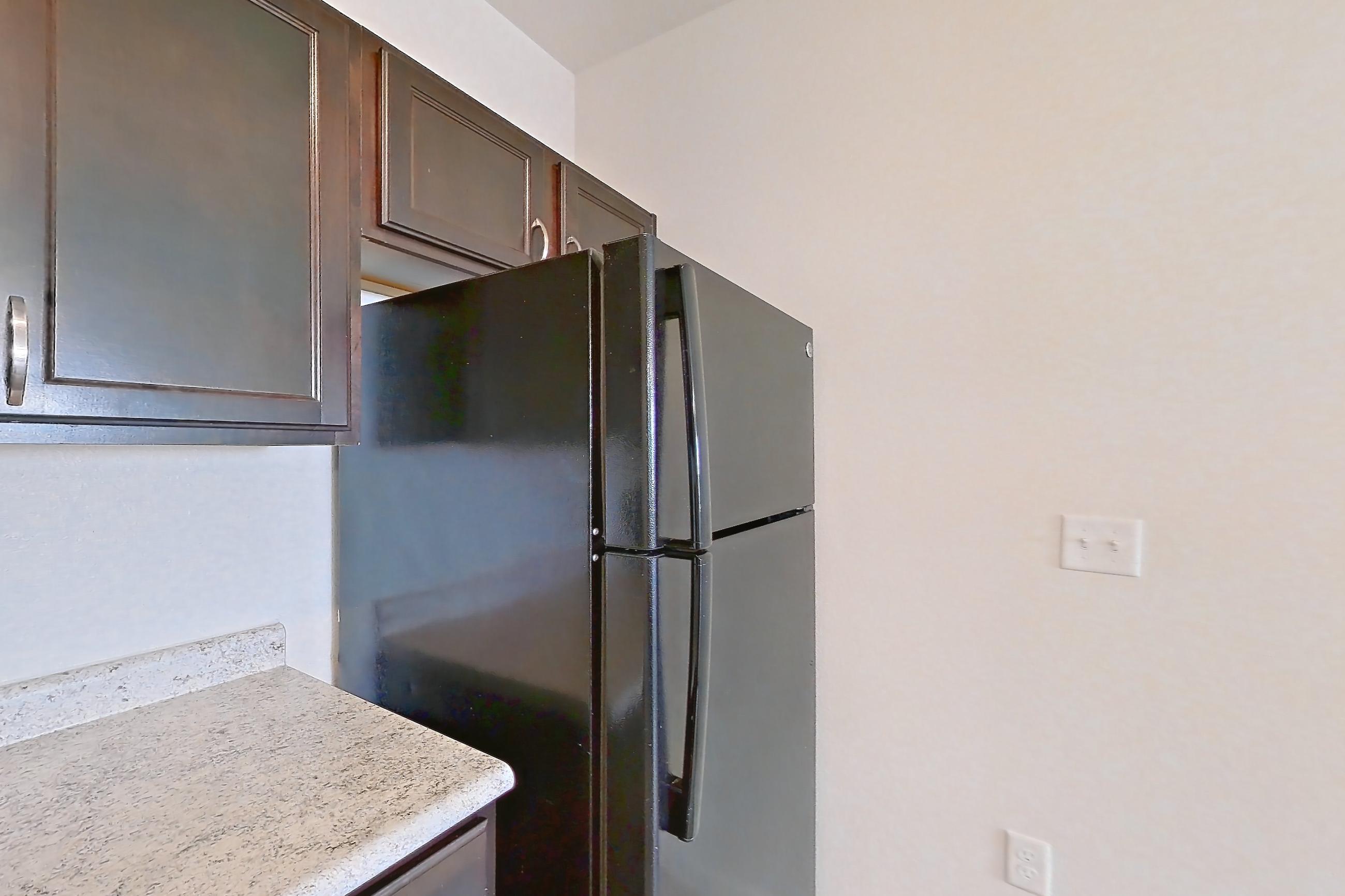 Kitchen with black appliances, dishwasher, electric range, light countertops, light stone countertops, light wood-finish flooring, oven/range, and refrigerator, Apartment 323 at Tuckaway