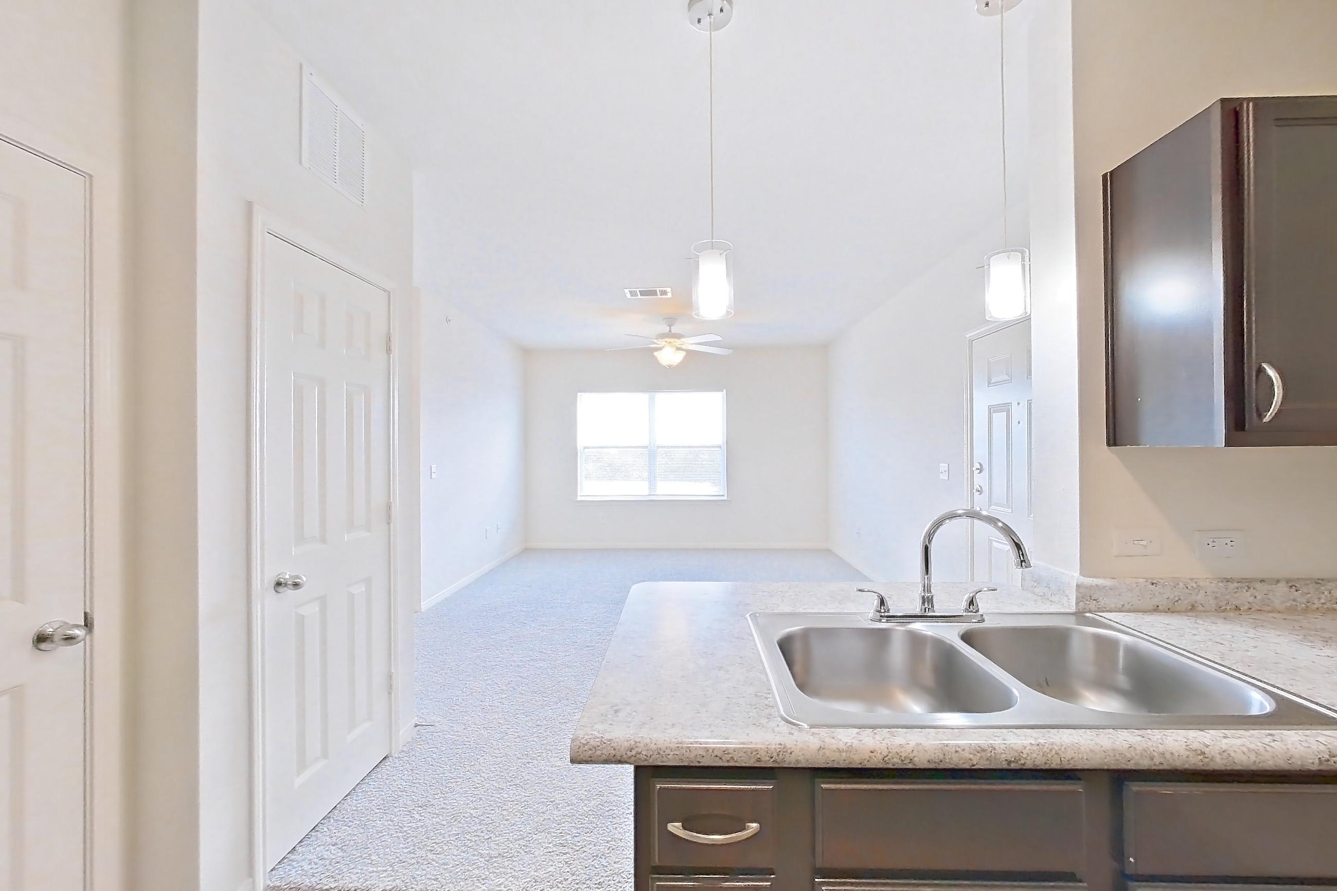 Kitchen with black appliances, dishwasher, electric range, light countertops, light stone countertops, light wood-finish flooring, oven/range, and refrigerator, Apartment 323 at Tuckaway