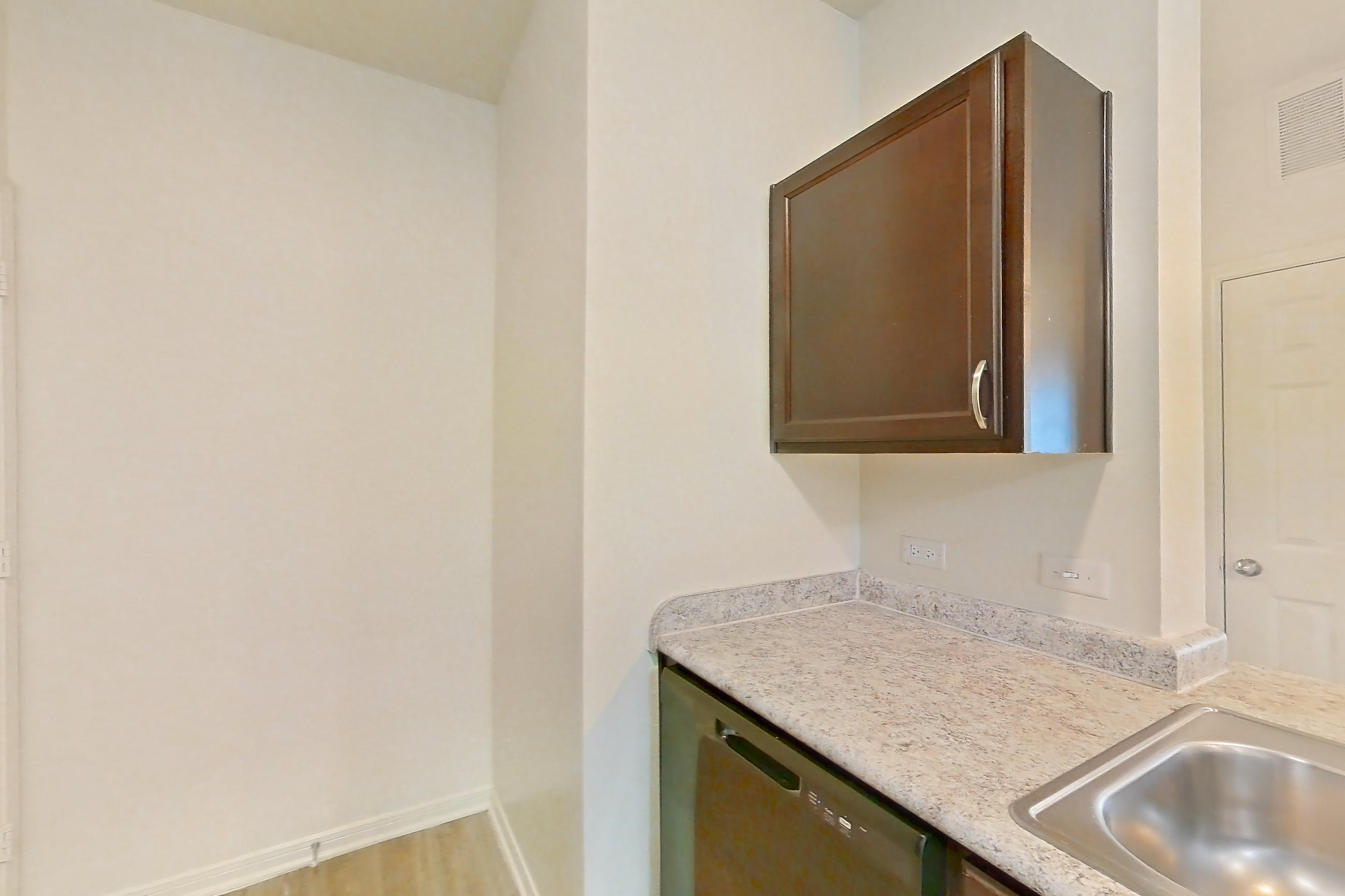 Kitchen with black appliances, electric range, light countertops, light stone countertops, light wood-finish flooring, oven/range, refrigerator, and stainless steel appliances, Apartment 913 at Tuckaway