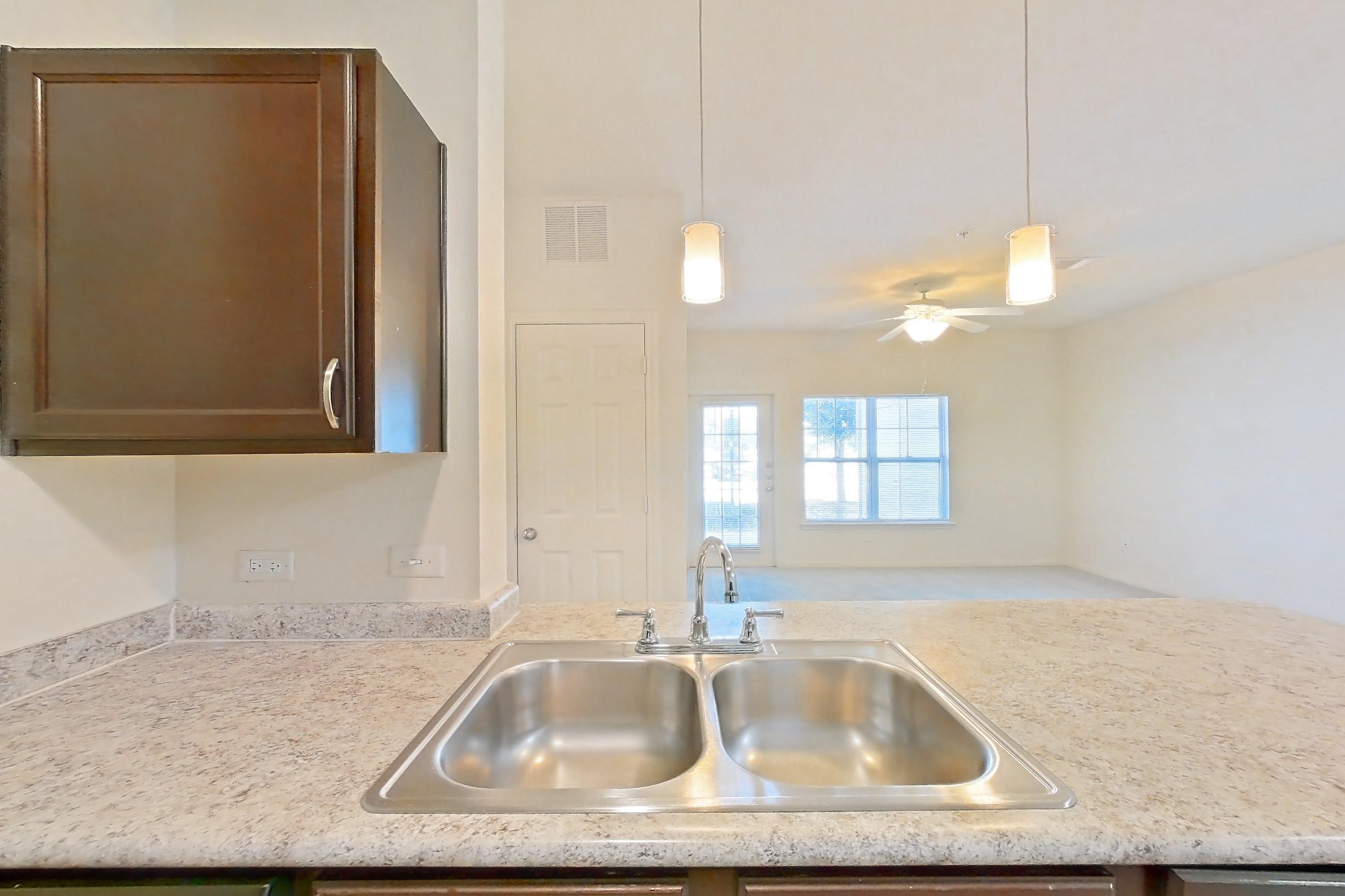 Kitchen with black appliances, electric range, light countertops, light stone countertops, light wood-finish flooring, oven/range, refrigerator, and stainless steel appliances, Apartment 913 at Tuckaway