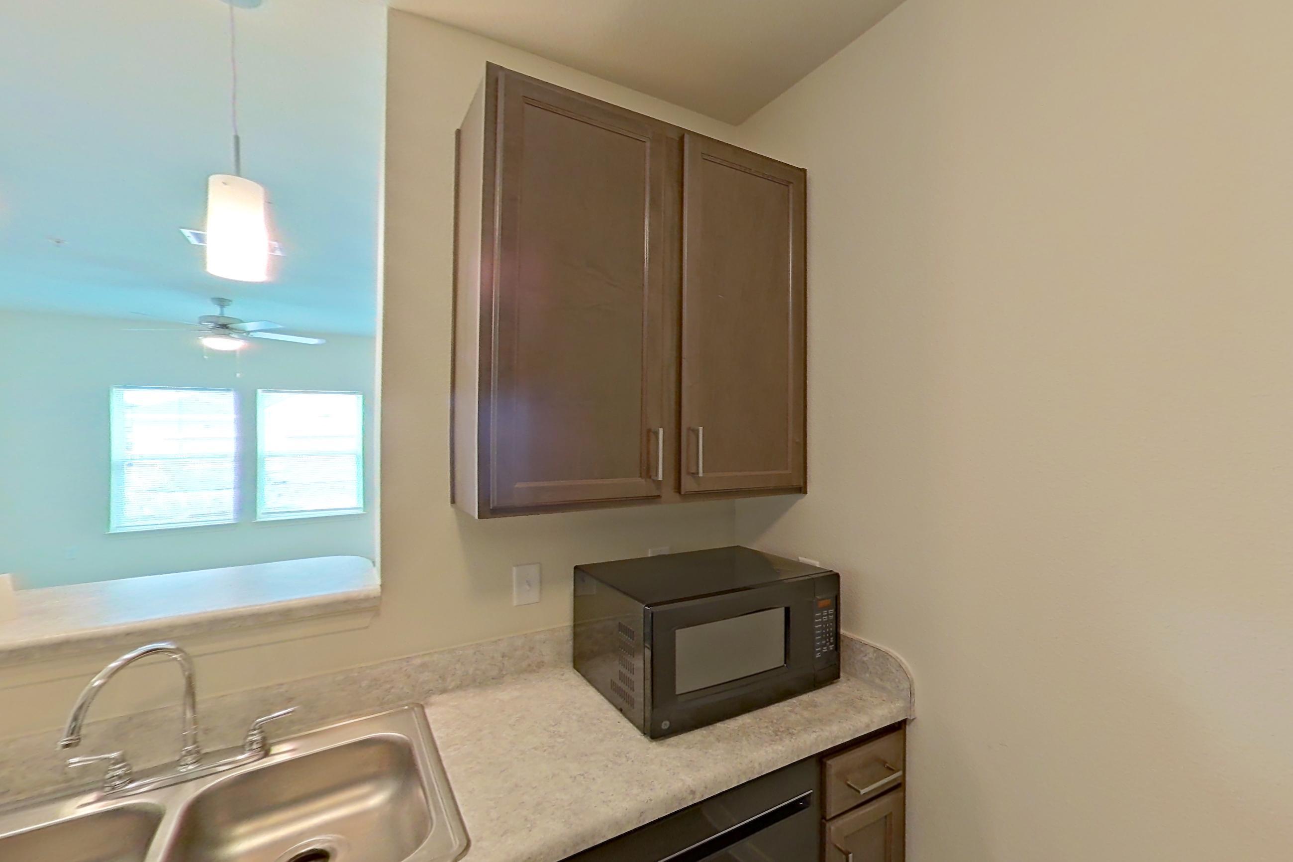 Kitchen with black appliances, dishwasher, electric range, light countertops, light wood-finish flooring, oven/range, refrigerator, and stainless steel appliances, Apartment 4104 at Denton Grove