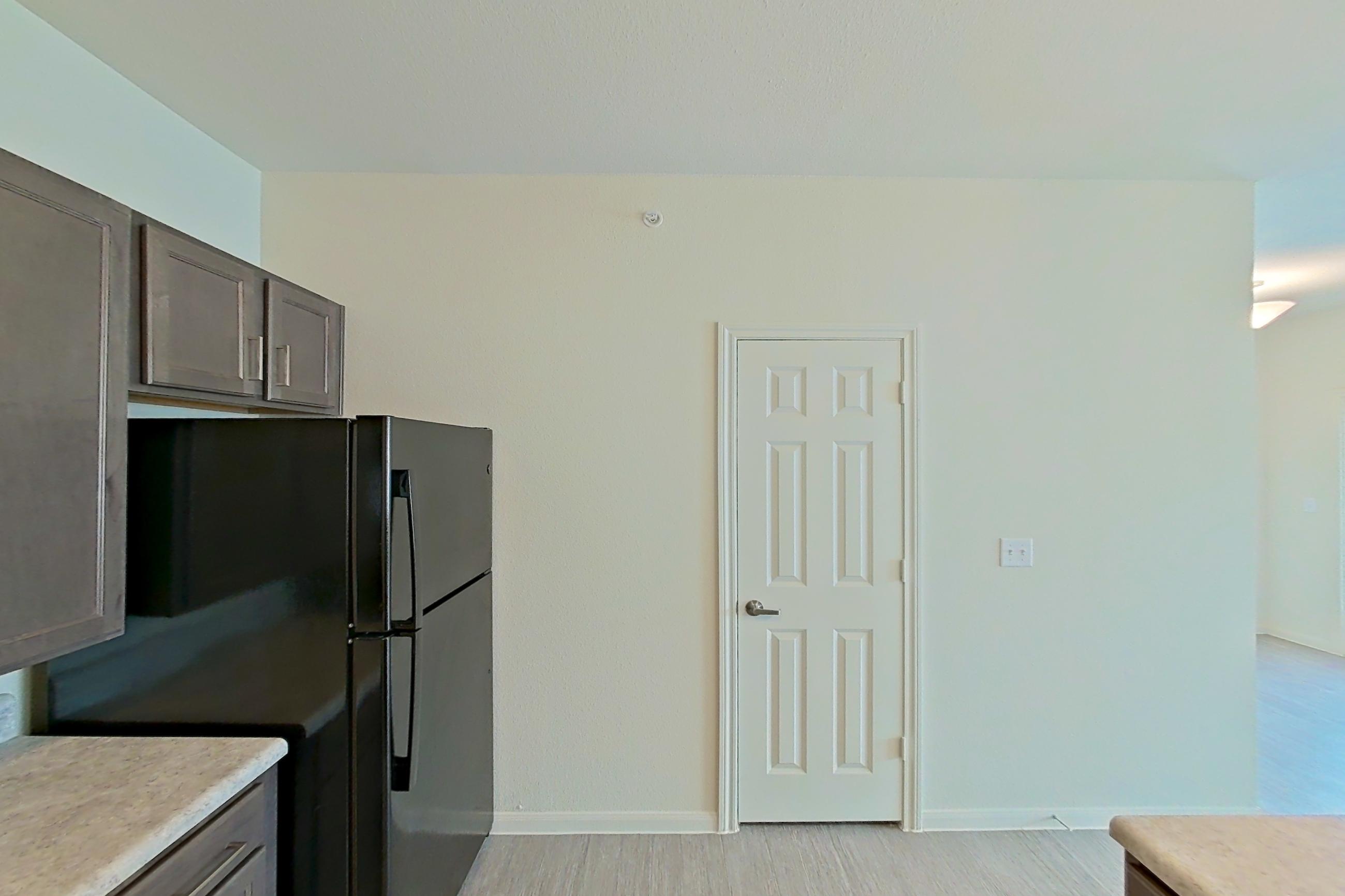 Kitchen with black appliances, dishwasher, electric range, light countertops, light wood-finish flooring, oven/range, refrigerator, and stainless steel appliances, Apartment 4104 at Denton Grove