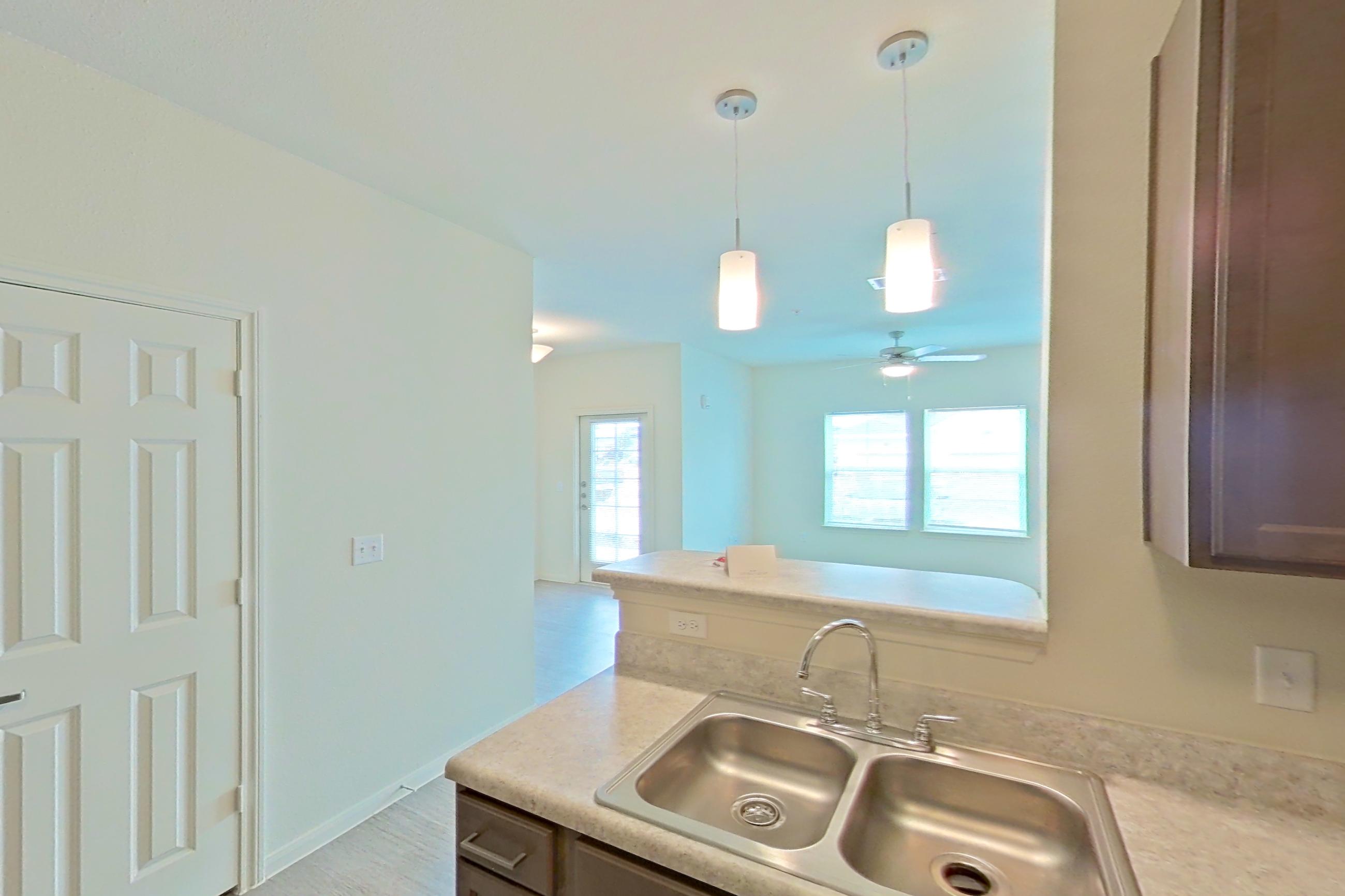 Kitchen with black appliances, dishwasher, electric range, light countertops, light wood-finish flooring, oven/range, refrigerator, and stainless steel appliances, Apartment 4104 at Denton Grove