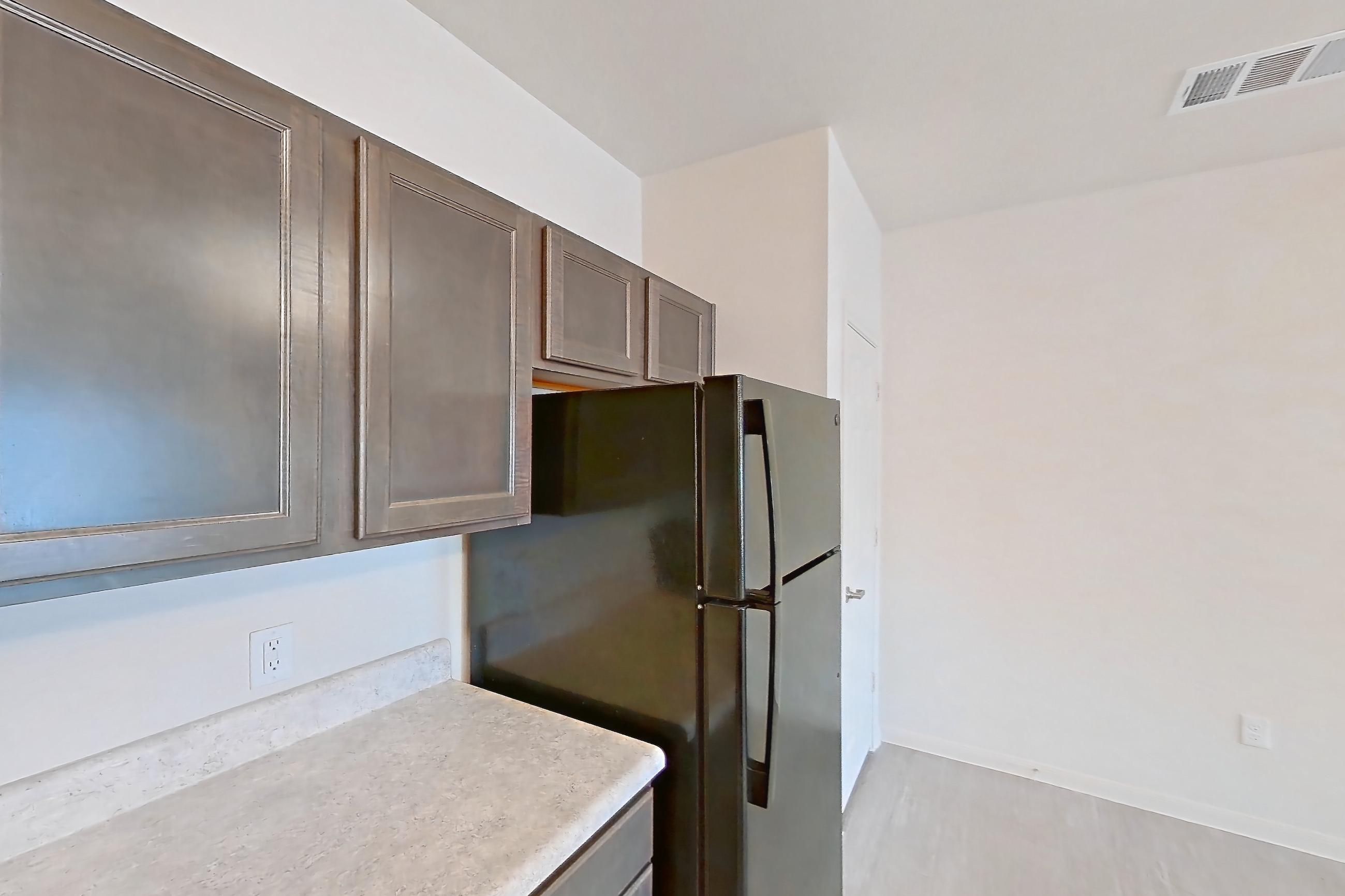 Kitchen with black appliances, dishwasher, electric range, light countertops, light wood-finish flooring, oven/range, refrigerator, and stainless steel appliances, Apartment 10208 at Denton Grove