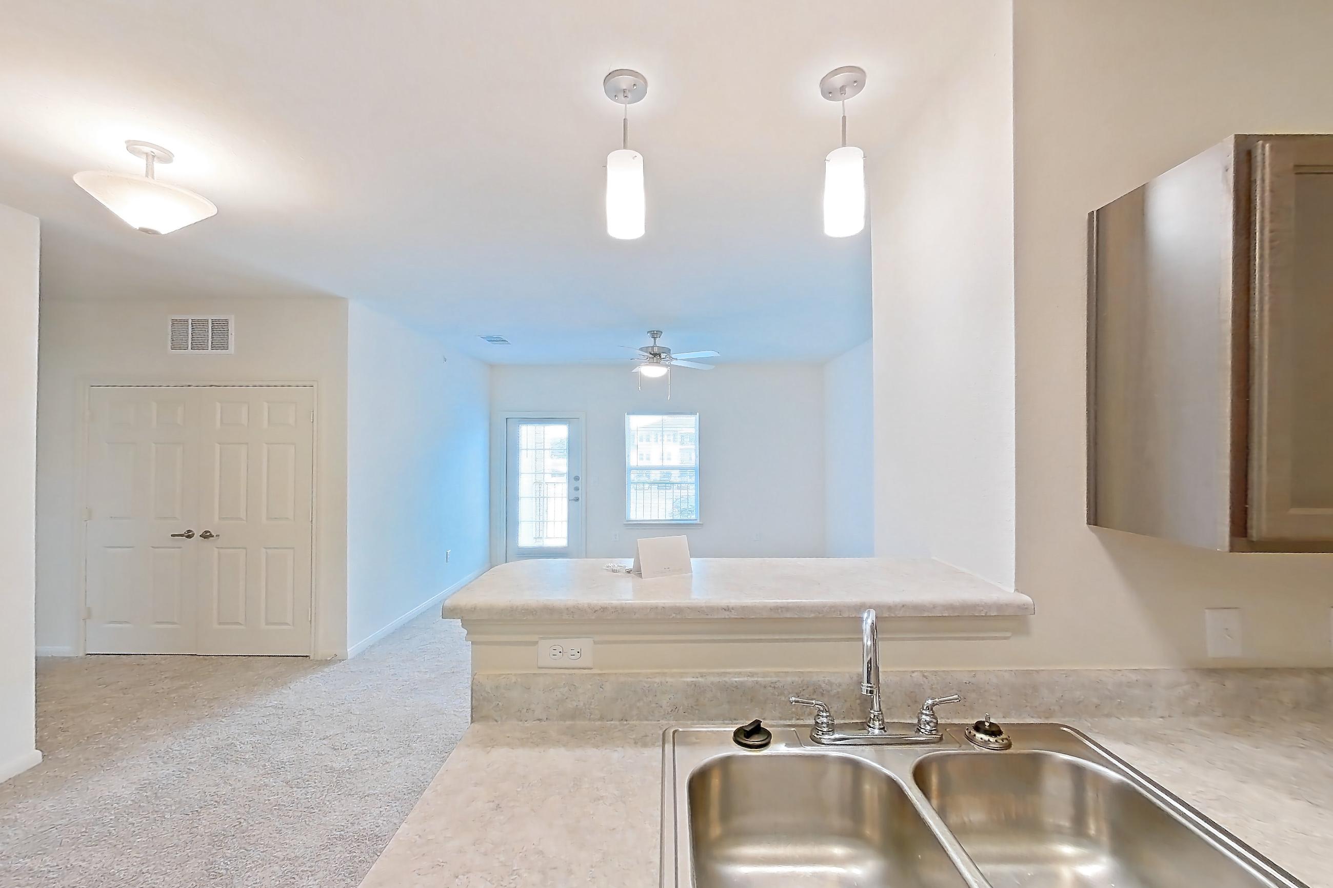 Kitchen with black appliances, dishwasher, electric range, light countertops, light wood-finish flooring, oven/range, refrigerator, and stainless steel appliances, Apartment 10208 at Denton Grove