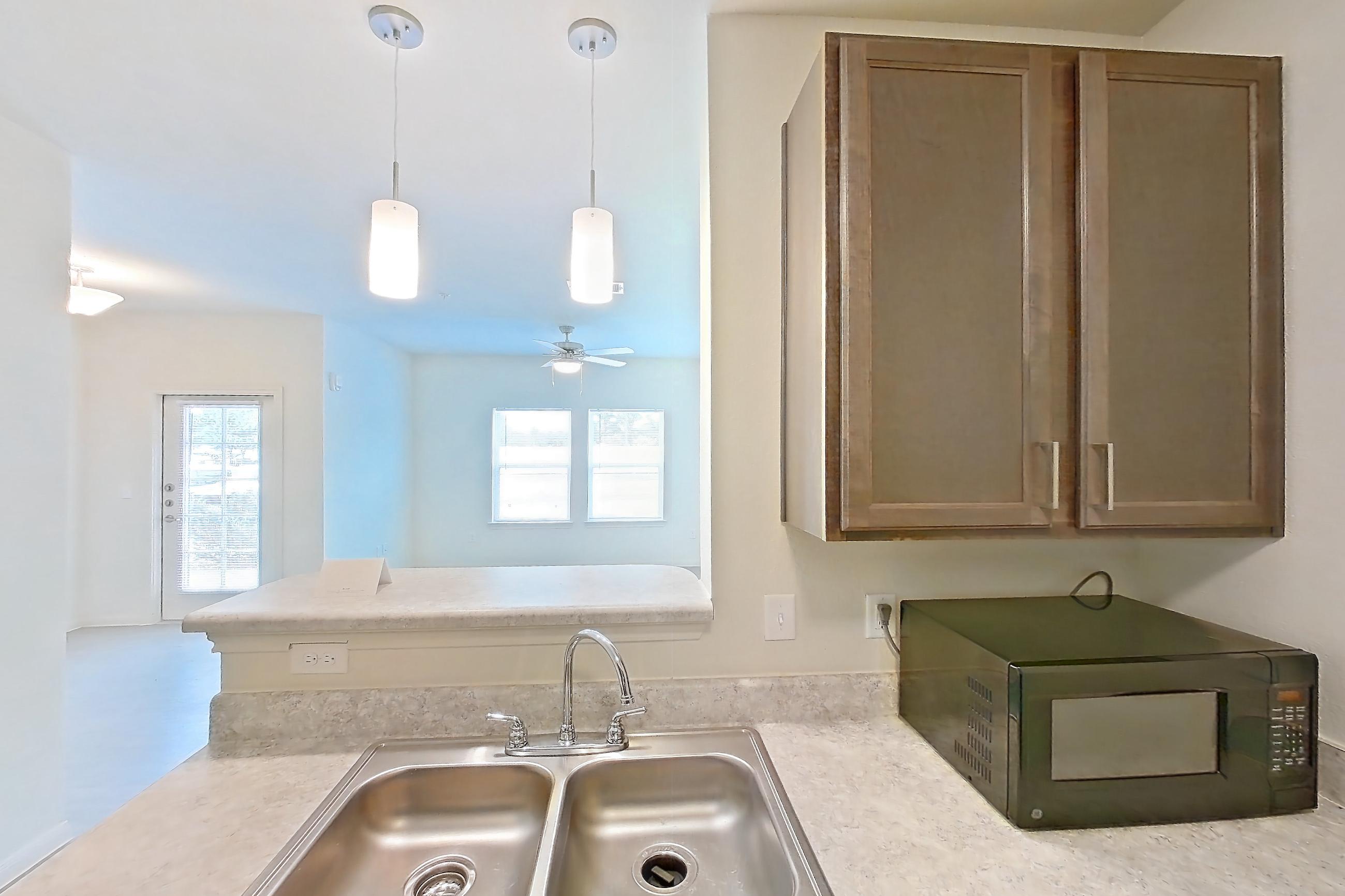 Kitchen with black appliances, electric range, light countertops, light wood-finish flooring, microwave, oven/range, and refrigerator, Apartment 8104 at Denton Grove