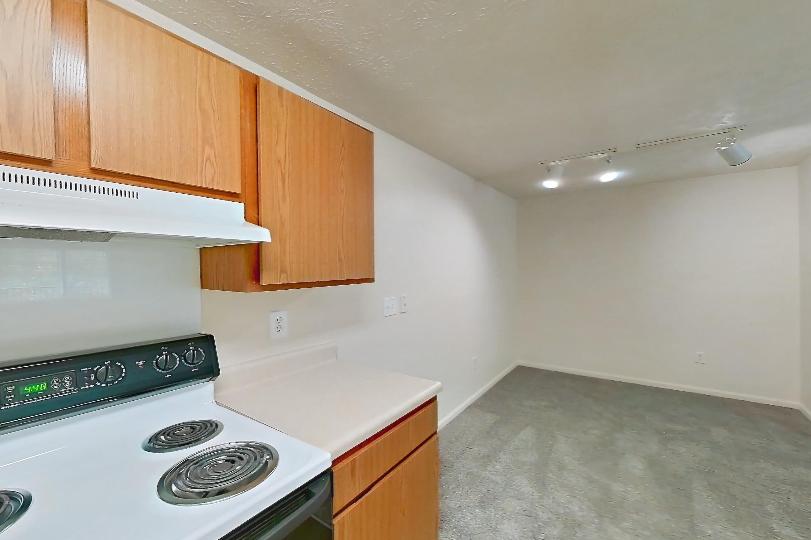 Kitchen with dark carpet, dark wood-finish flooring, dishwasher, electric range, light countertops, oven/range, refrigerator, and white appliances, Apartment 8102-K at Crooked Creek