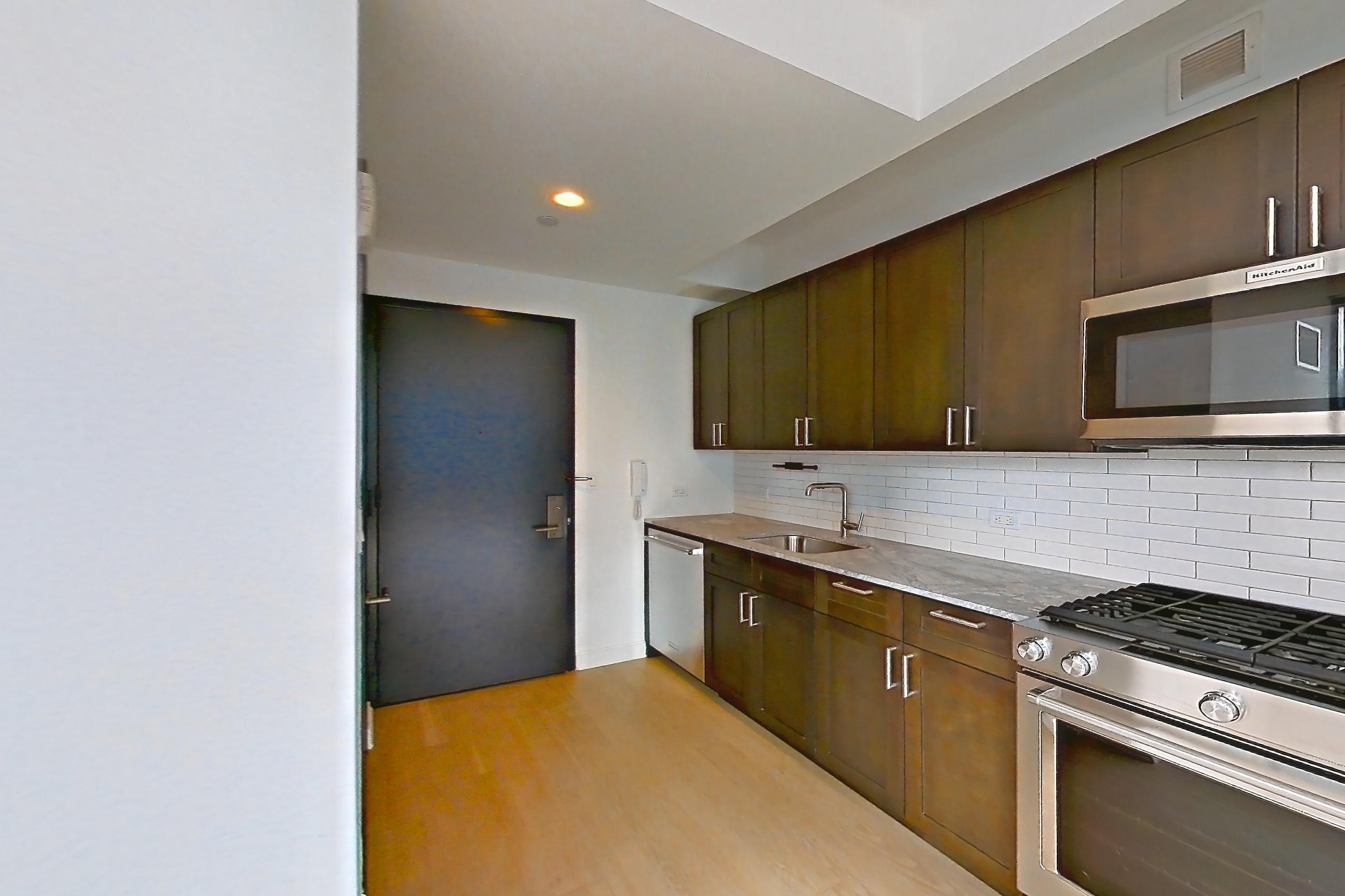 Kitchen with dishwasher, gas range, light countertops, light stone countertops, light wood-finish flooring, microwave, oven/range, refrigerator, skyline view, and stainless steel appliances, Apartment 2211 at 21 West End Avenue