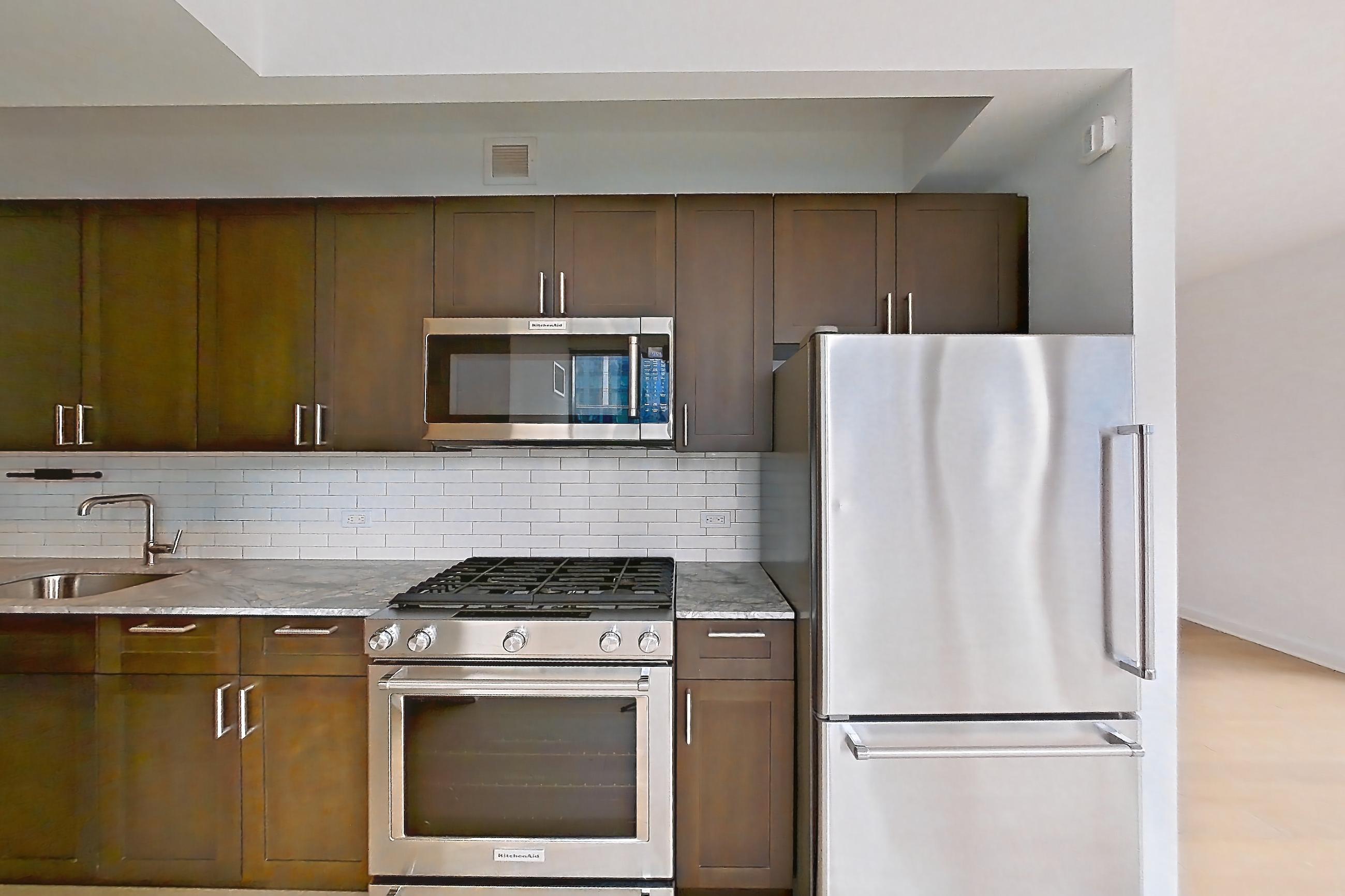 Kitchen with dishwasher, gas range, light countertops, light stone countertops, light wood-finish flooring, microwave, oven/range, refrigerator, skyline view, and stainless steel appliances, Apartment 2211 at 21 West End Avenue