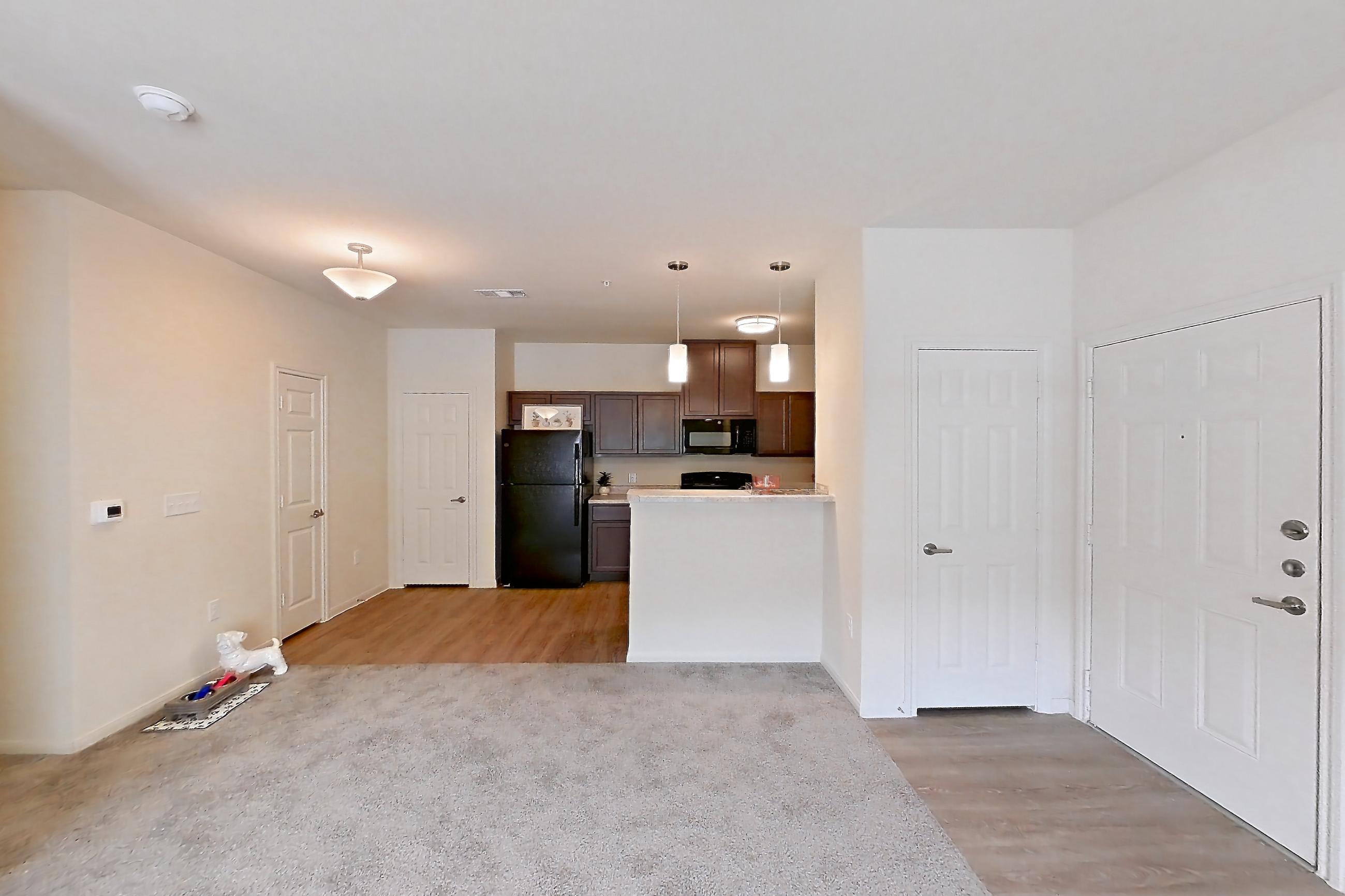 Living room with black appliances, light carpet, and refrigerator, Apartment 7103 at Mill Stream