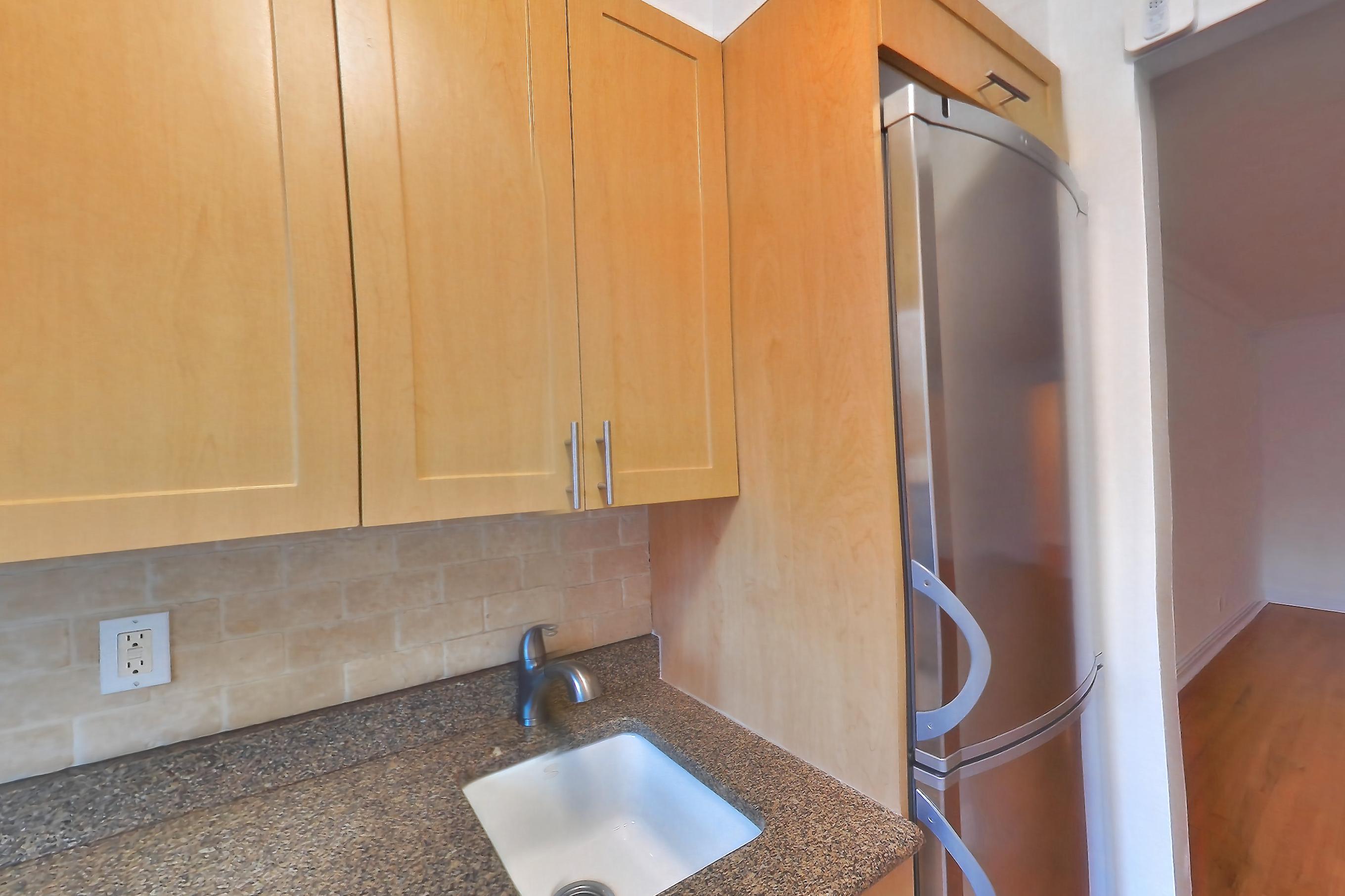 Kitchen with dark stone countertops, dishwasher, gas range, light tile flooring, microwave, oven/range, refrigerator, and stainless steel appliances, Apartment 7N at Stonehenge Leasing