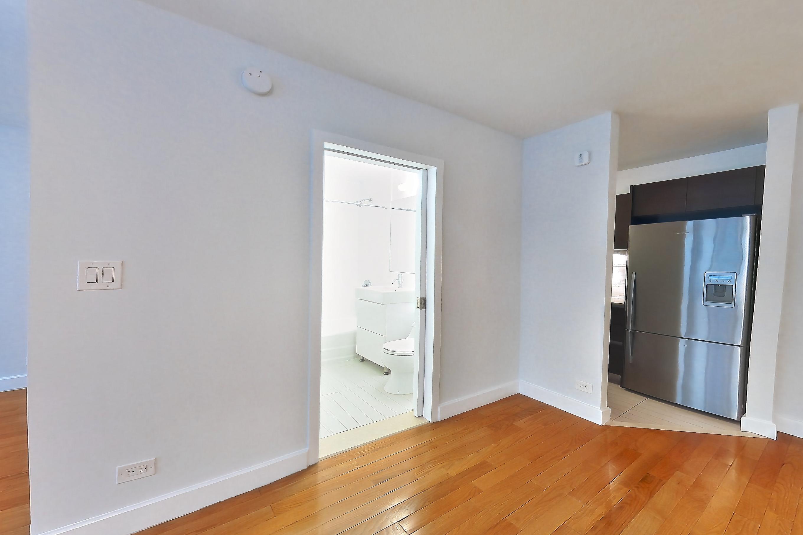 Living room with air conditioning, light wood-finish flooring, refrigerator, stainless steel appliances, and wood-finish flooring, Apartment 5B at Stonehenge Leasing