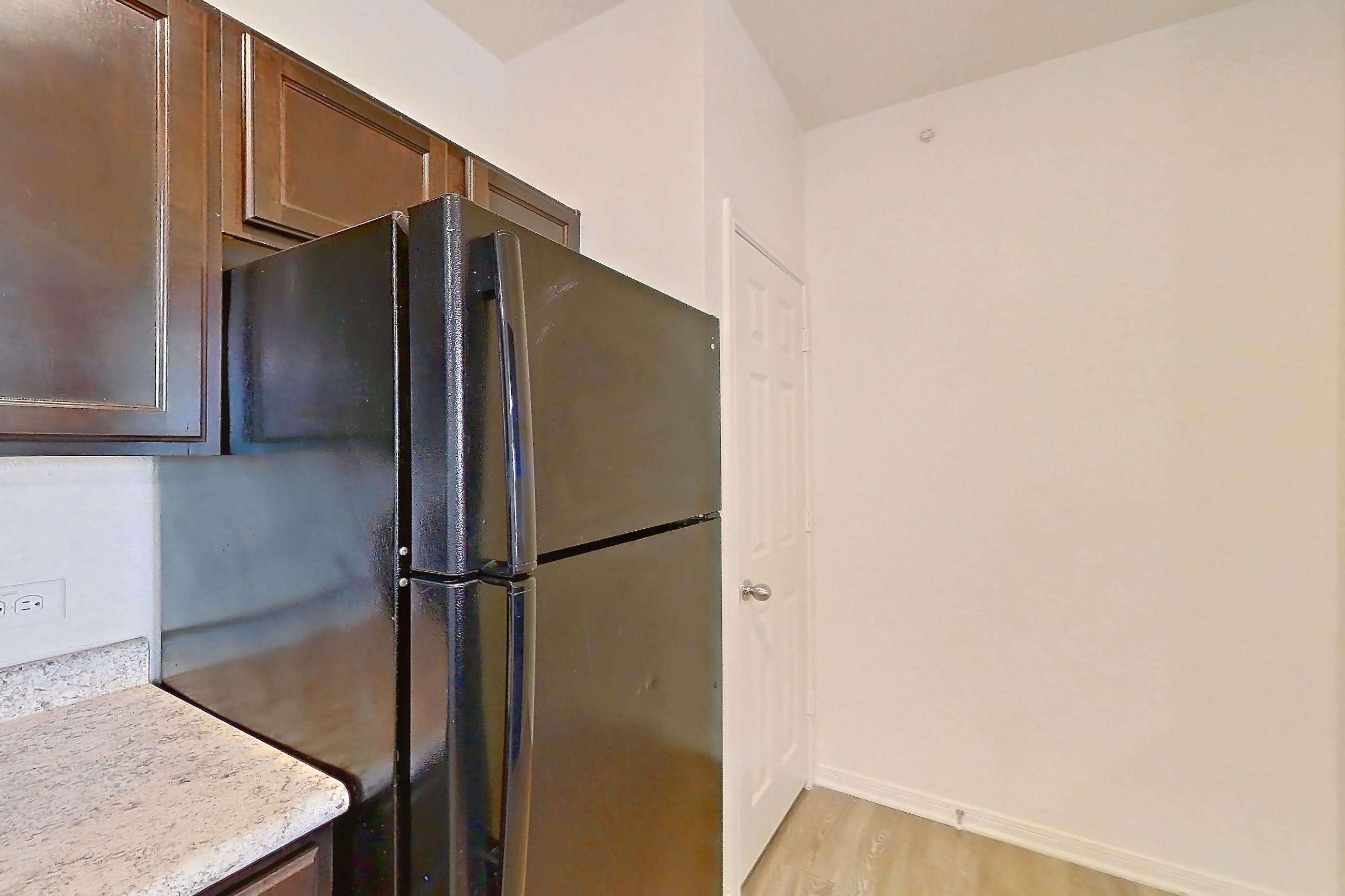Kitchen with black appliances, dishwasher, electric range, light countertops, light stone countertops, light wood-finish flooring, and oven/range, Apartment 632 at Tuckaway