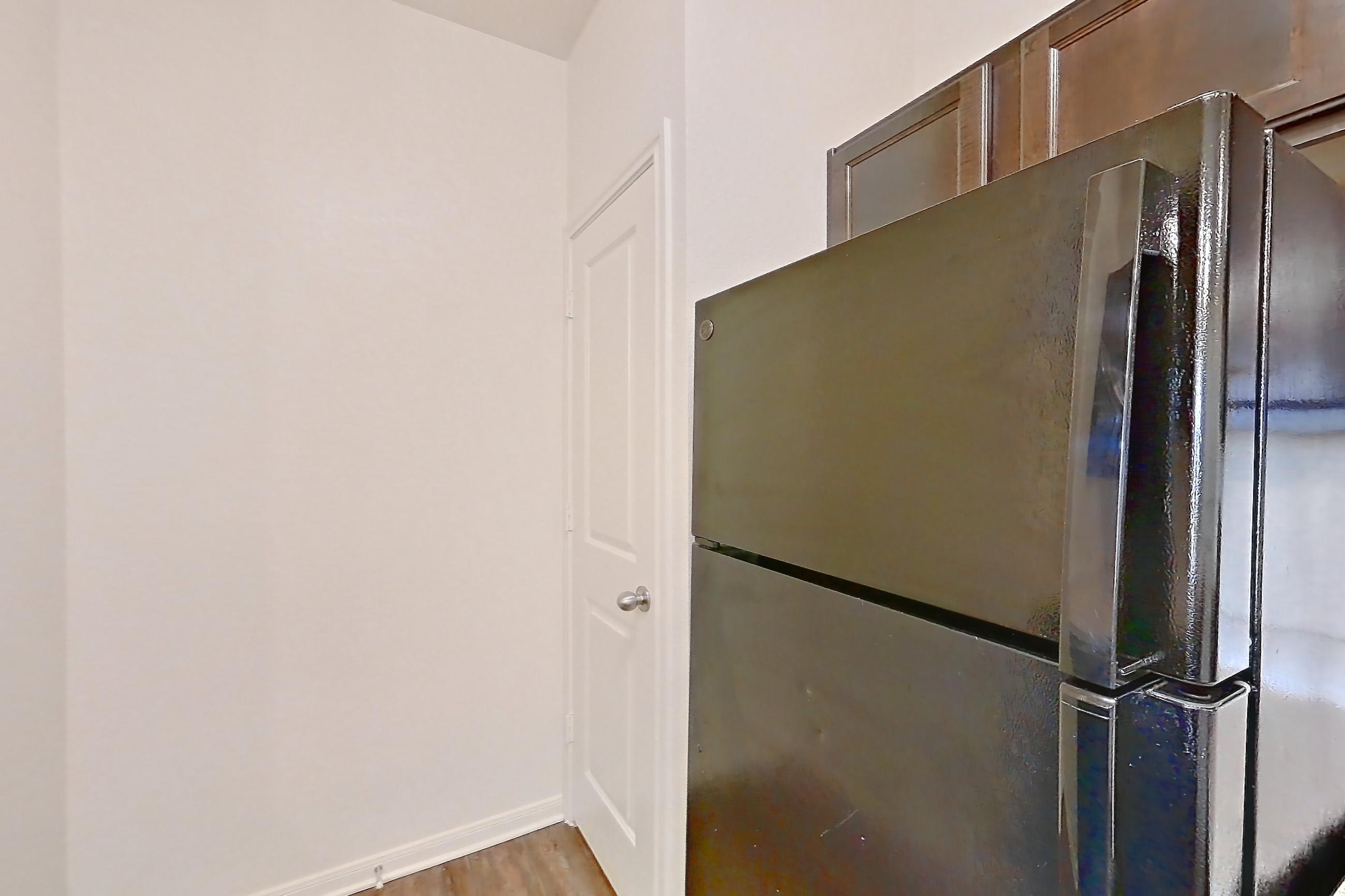 Kitchen with black appliances, dishwasher, electric range, light carpet, light countertops, light stone countertops, light wood-finish flooring, oven/range, refrigerator, and stainless steel appliances, Apartment 1231 at The Heights on Parmer