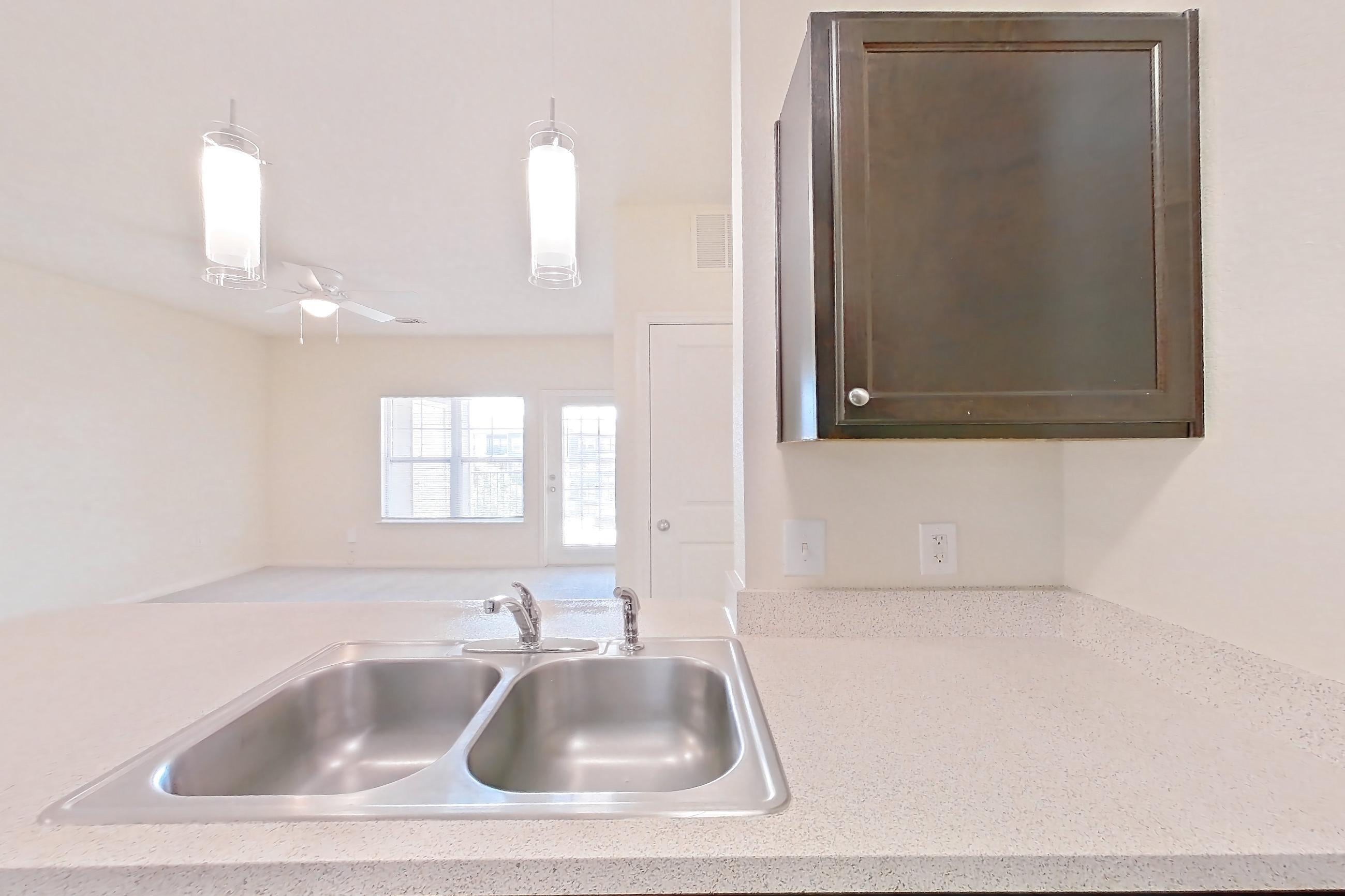 Kitchen with black appliances, dishwasher, electric range, light carpet, light countertops, light stone countertops, light wood-finish flooring, oven/range, refrigerator, and stainless steel appliances, Apartment 1231 at The Heights on Parmer