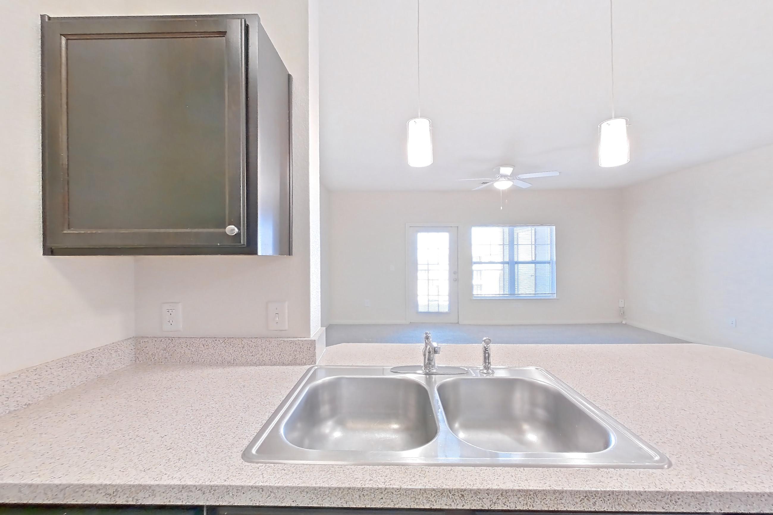 Kitchen with black appliances, dark carpet, dark wood-finish flooring, dishwasher, electric range, light countertops, light stone countertops, oven/range, refrigerator, and stainless steel appliances, Apartment 1033 at The Heights on Parmer