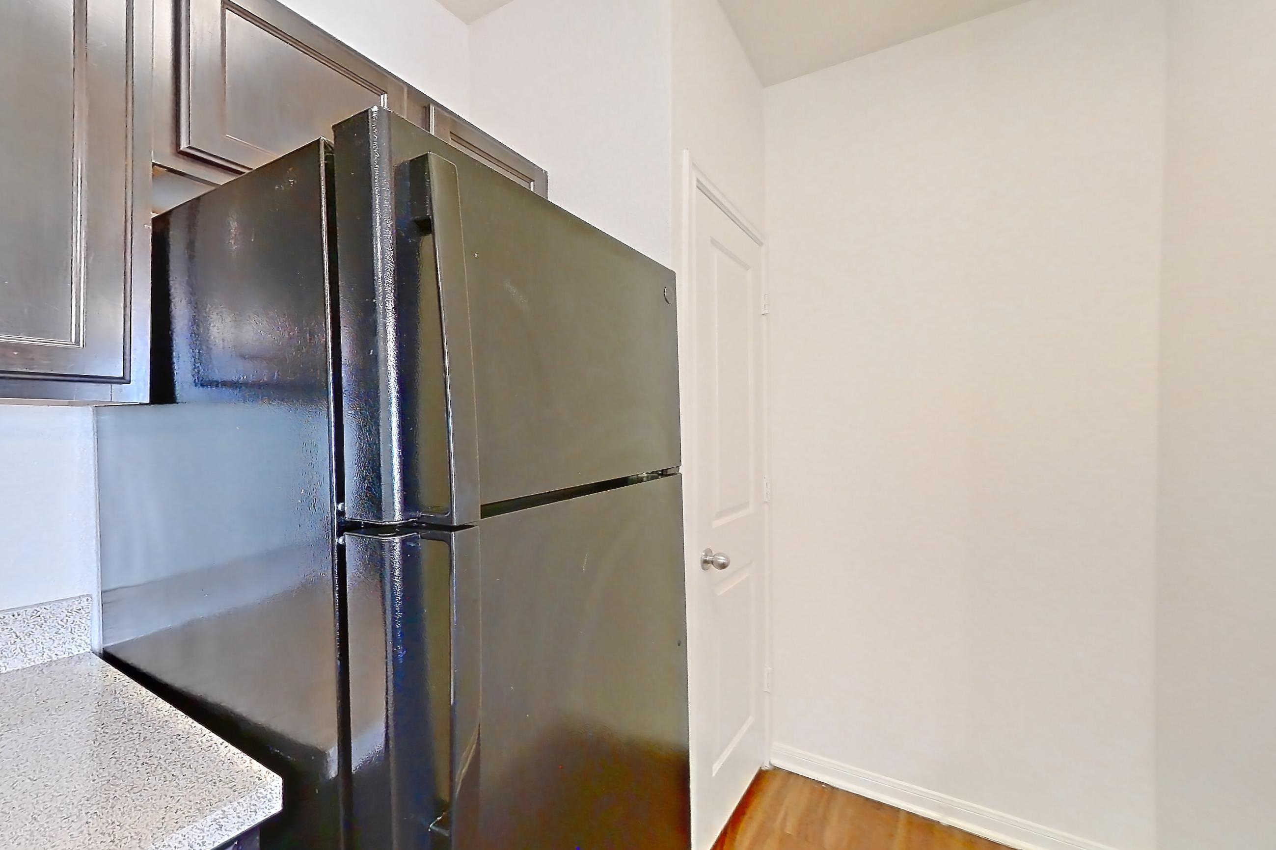 Kitchen with black appliances, dark carpet, dark wood-finish flooring, dishwasher, electric range, light countertops, light stone countertops, oven/range, refrigerator, and stainless steel appliances, Apartment 1033 at The Heights on Parmer