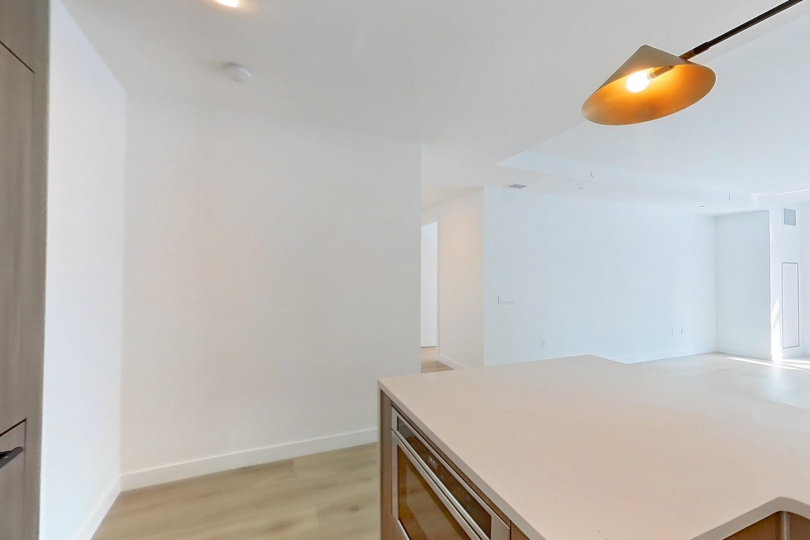 Kitchen with kitchen island, light stone countertops, light wood-finish flooring, microwave, and stainless steel appliances, Apartment 08B at Maison 78