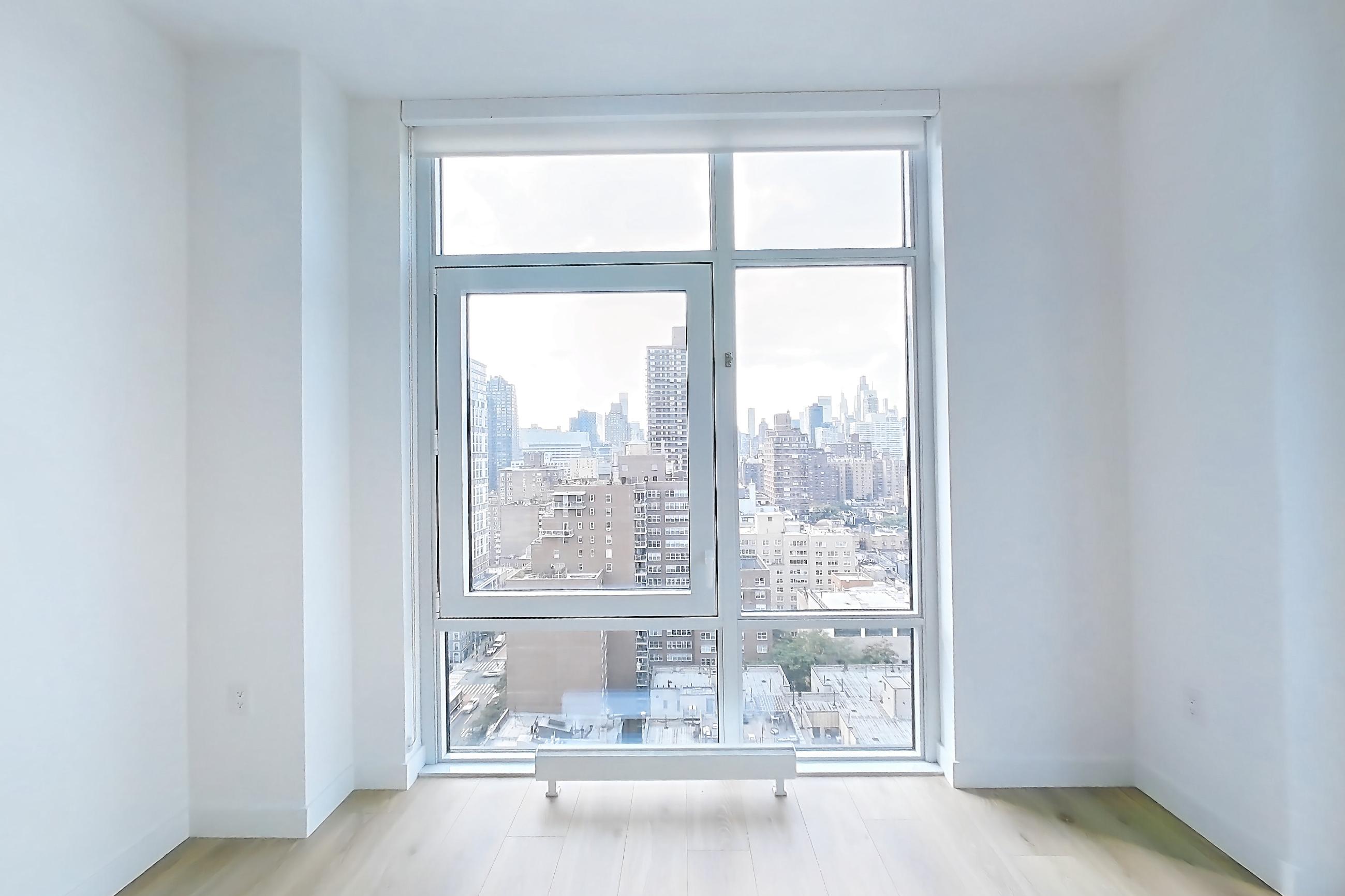 Living room with light wood-finish flooring and skyline view, Apartment 19D at Maison 78