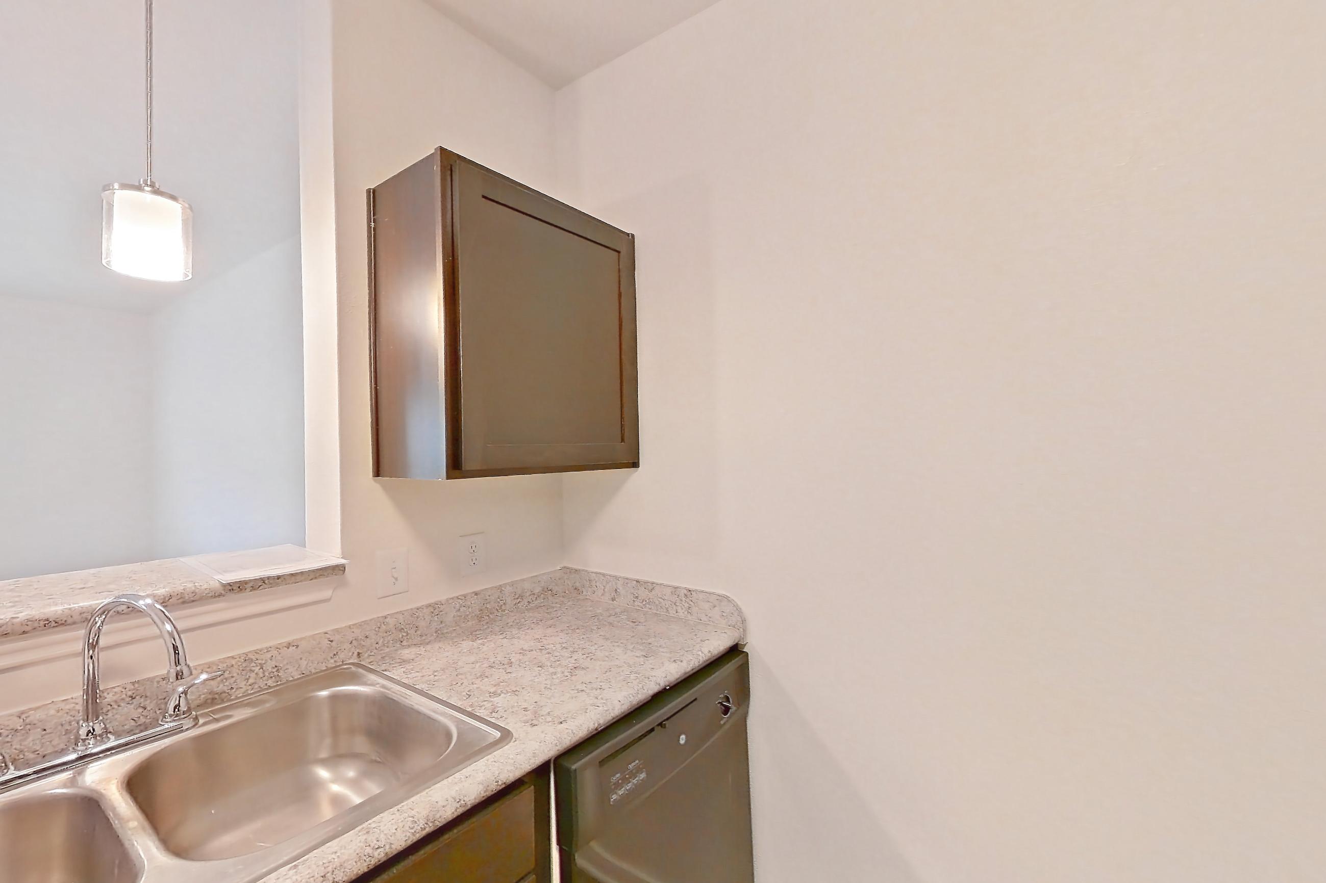 Kitchen with black appliances, dishwasher, electric range, light countertops, light stone countertops, light wood-finish flooring, microwave, oven/range, refrigerator, and stainless steel appliances, Apartment 2107 at Oak Valley