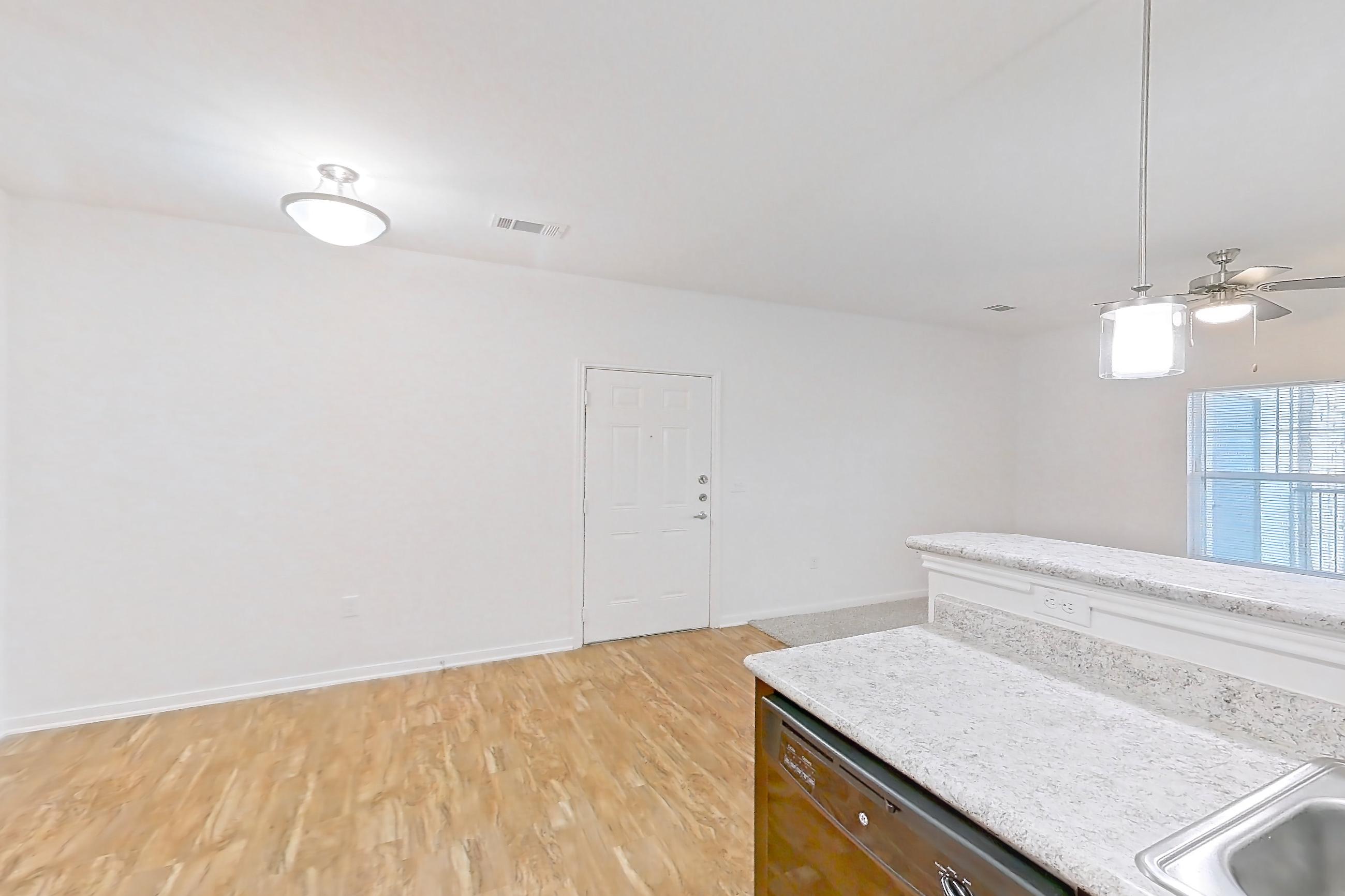 Kitchen with black appliances, dishwasher, electric range, light countertops, light stone countertops, light wood-finish flooring, oven/range, refrigerator, and stainless steel appliances, Apartment 1204 at Oak Valley