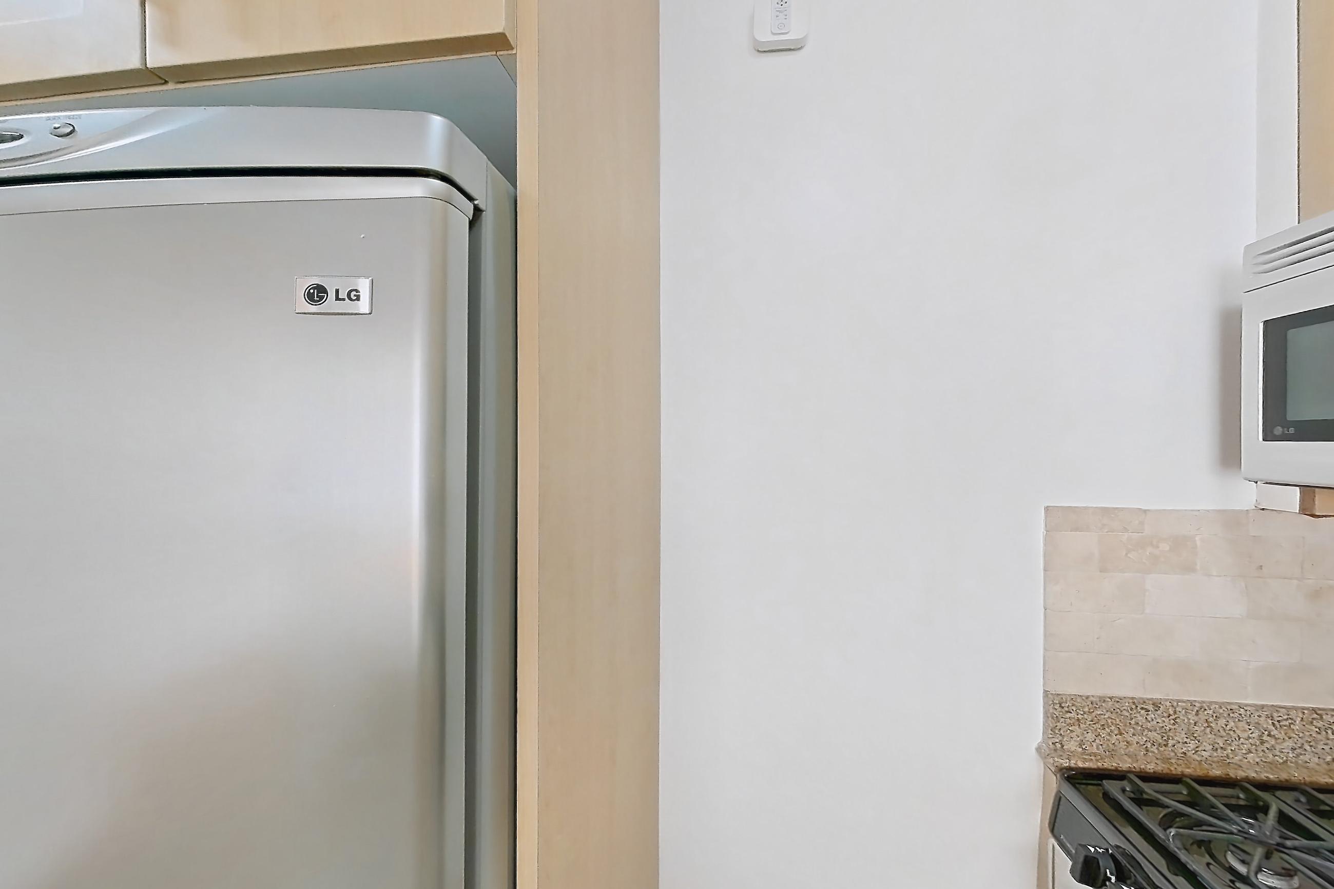 Kitchen with dishwasher, gas range, light countertops, light stone countertops, light wood-finish flooring, microwave, oven/range, refrigerator, stainless steel appliances, and white appliances, Apartment 6F at Stonehenge Leasing