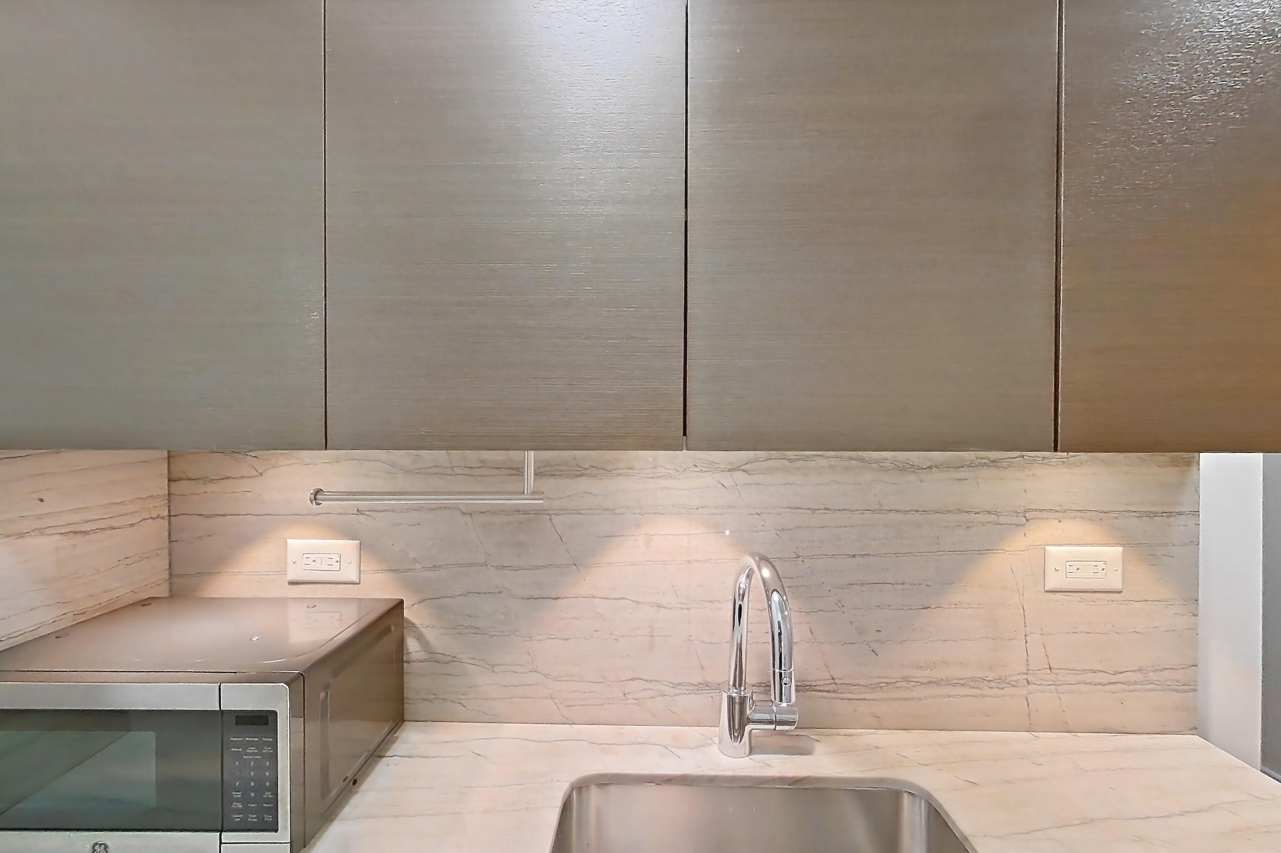 Kitchen with dishwasher, gas range, light countertops, light stone countertops, light wood-finish flooring, microwave, oven/range, stainless steel appliances, and wood-finish flooring, Apartment 6F at Stonehenge Leasing