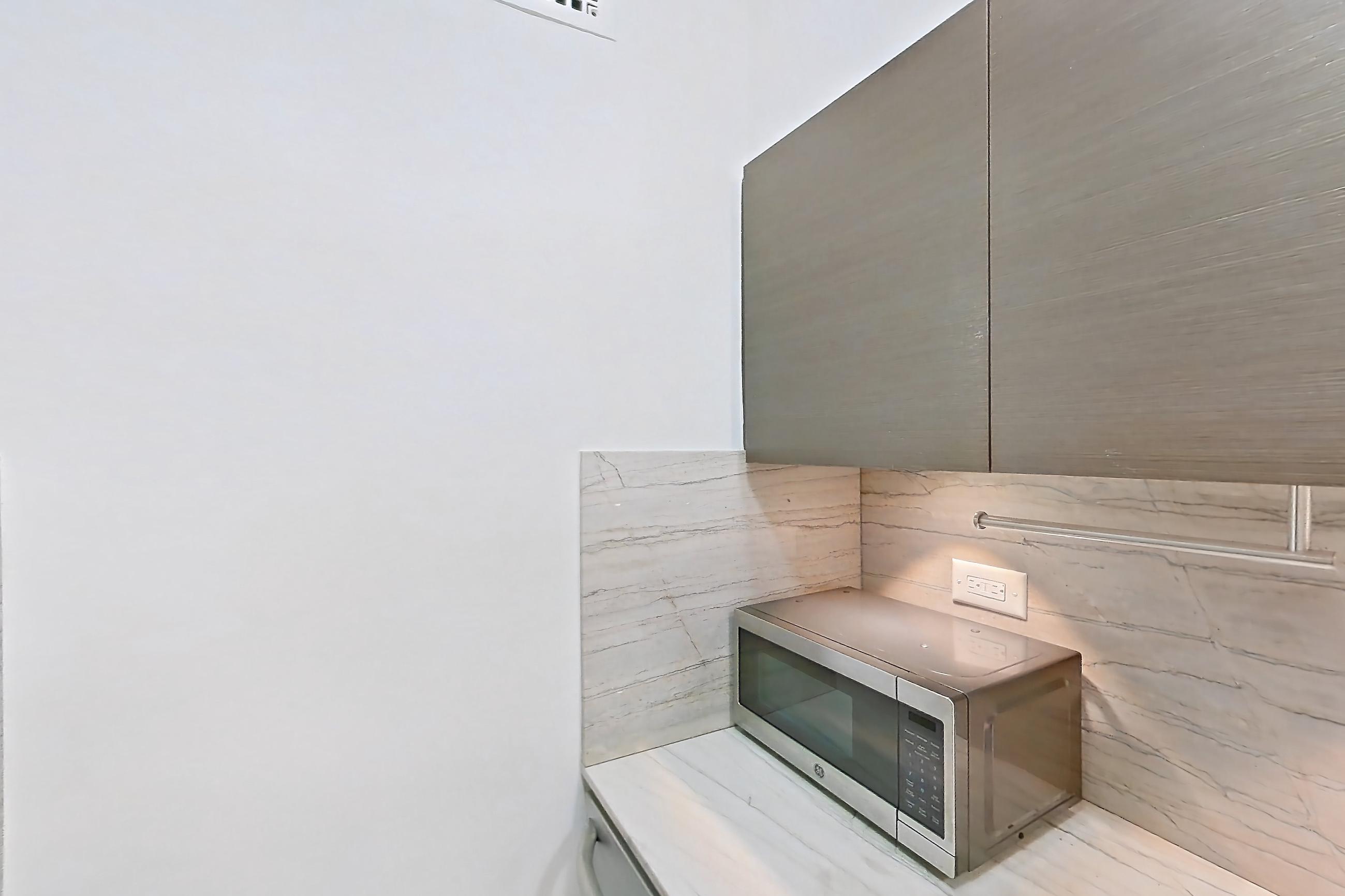 Kitchen with dishwasher, gas range, light countertops, light stone countertops, light wood-finish flooring, microwave, oven/range, stainless steel appliances, and wood-finish flooring, Apartment 6F at Stonehenge Leasing