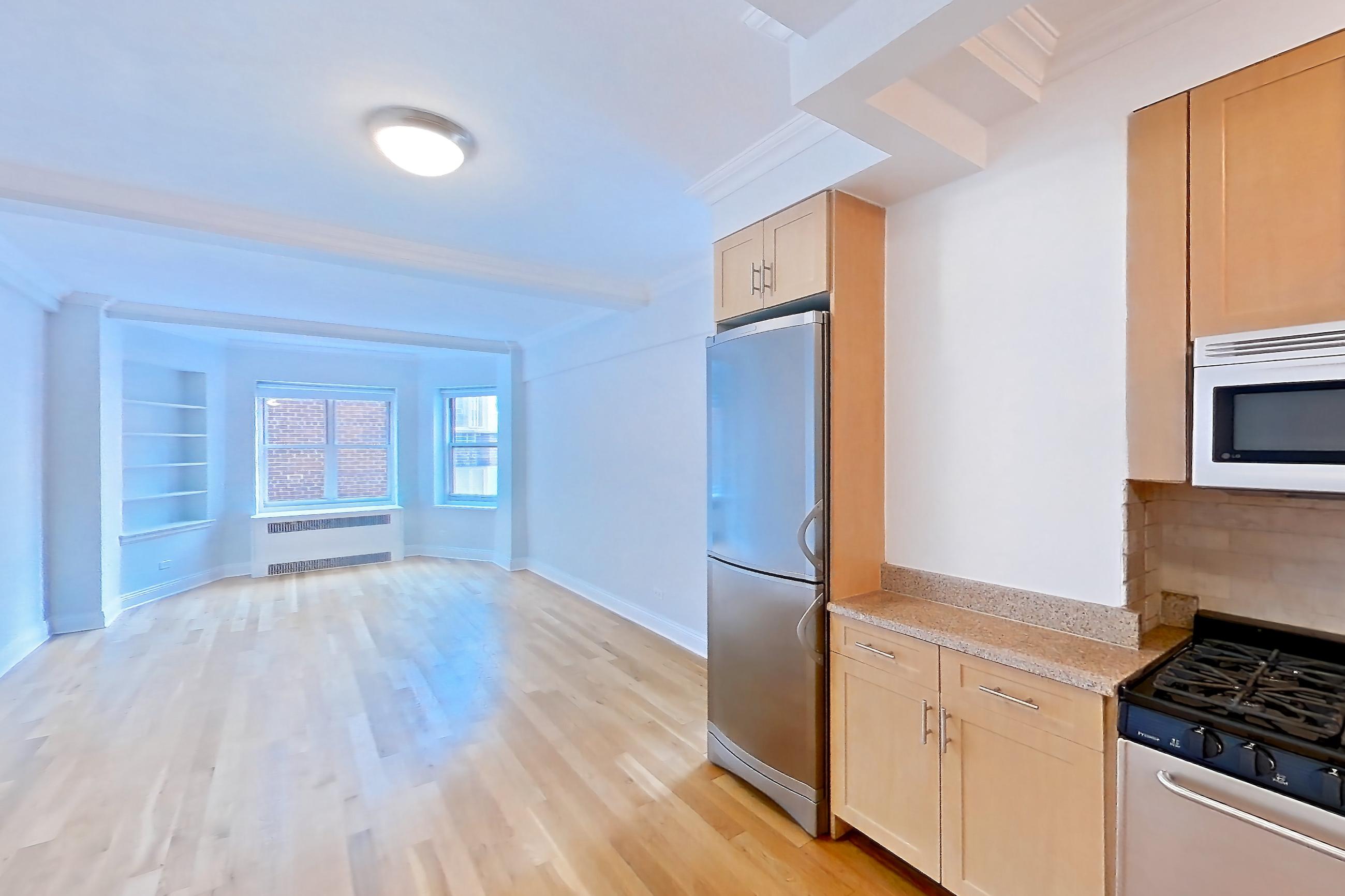 Kitchen with dishwasher, gas range, light countertops, light stone countertops, light wood-finish flooring, microwave, oven/range, refrigerator, stainless steel appliances, and white appliances, Apartment 9G at Stonehenge Leasing
