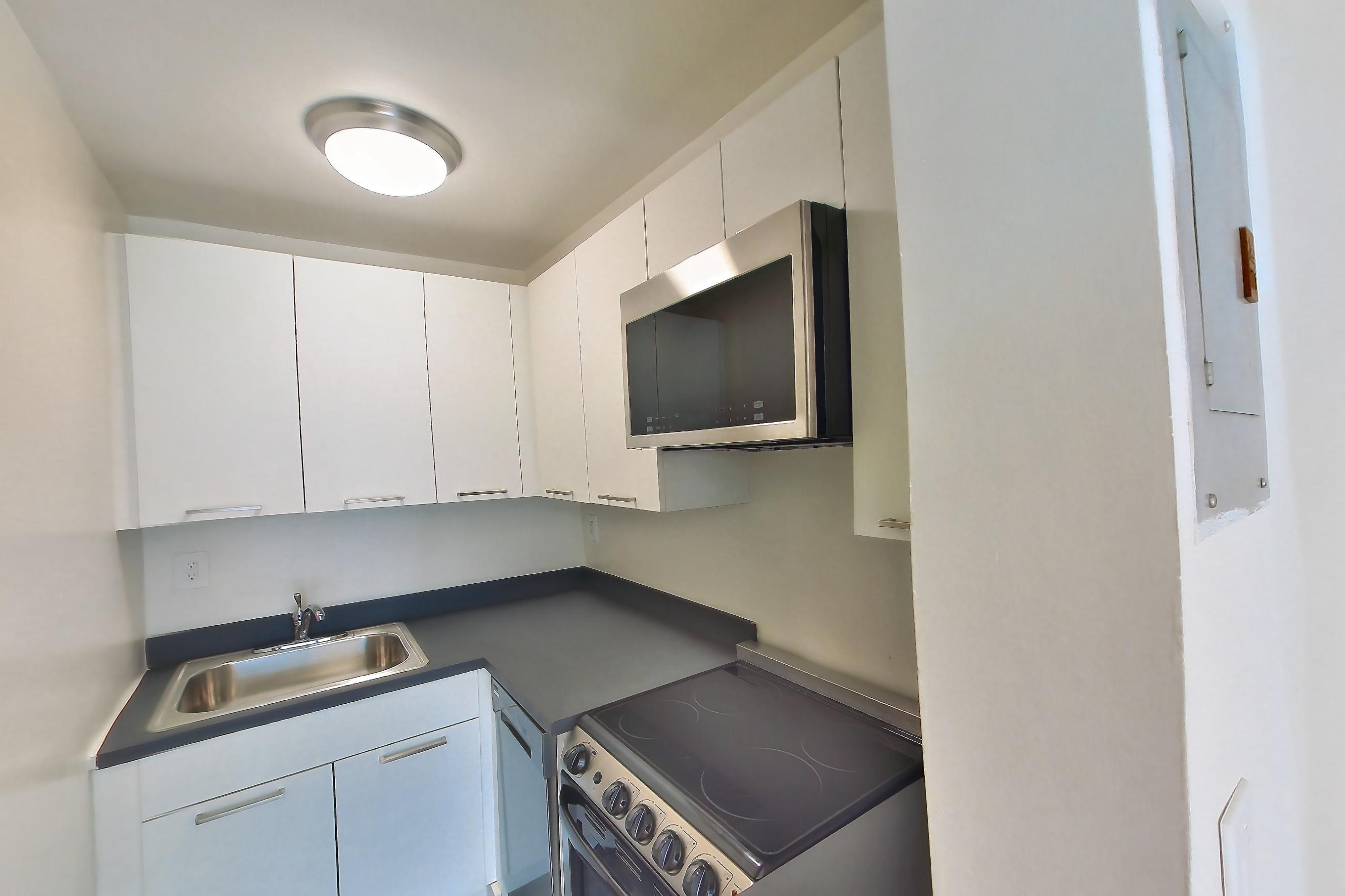 Kitchen with dark countertops, dark wood-finish flooring, electric range, oven/range, and stainless steel appliances, Apartment 5B at Bettina Equities