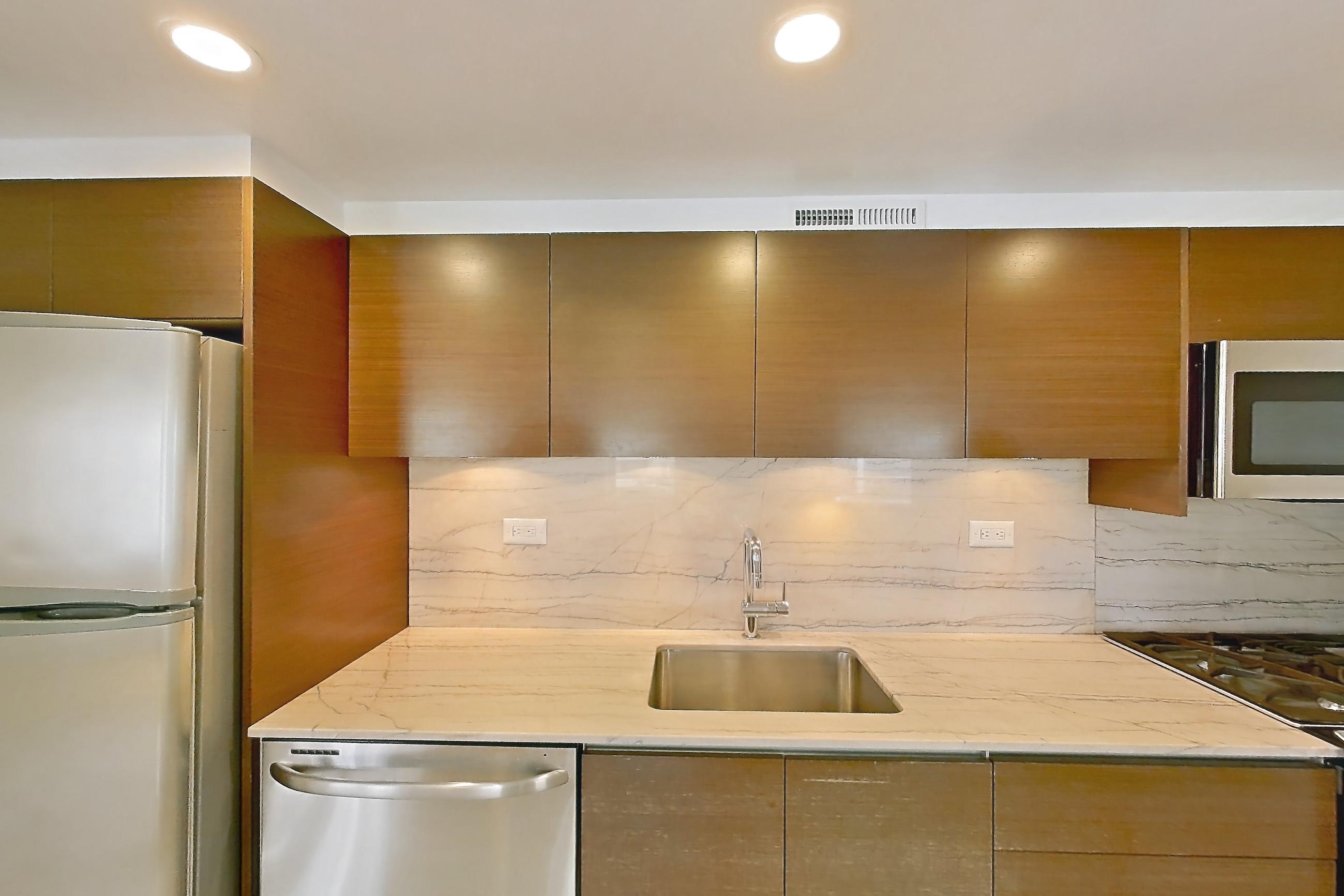 Kitchen with dishwasher, gas range, light countertops, light stone countertops, light tile flooring, light wood-finish flooring, oven/range, refrigerator, stainless steel appliances, white appliances, and wood-finish flooring, Apartment 5E at Stonehenge Leasing