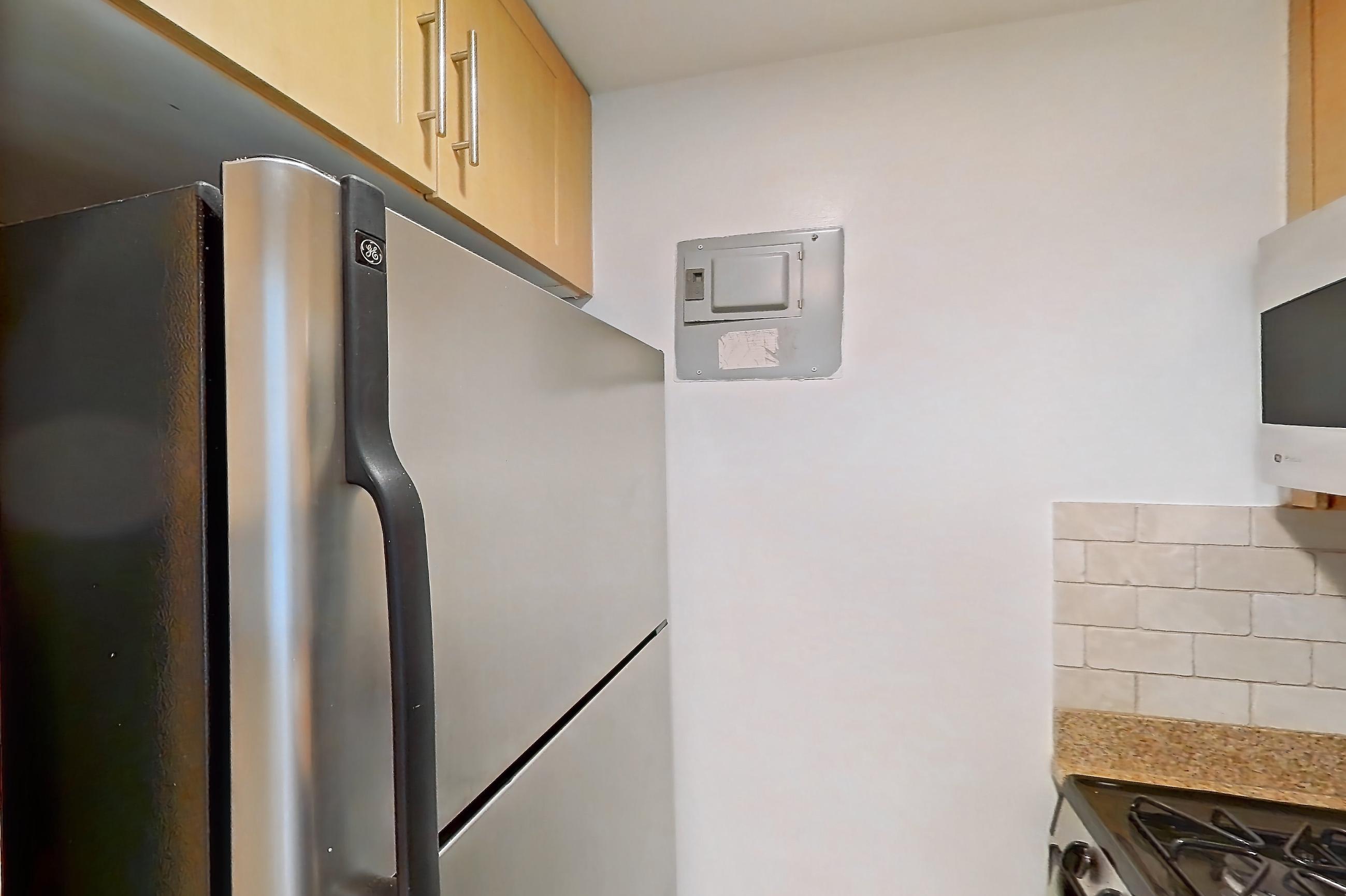 Kitchen with black appliances, dishwasher, gas range, light countertops, light stone countertops, light tile flooring, microwave, oven/range, and stainless steel appliances, Apartment 11D at Stonehenge Leasing