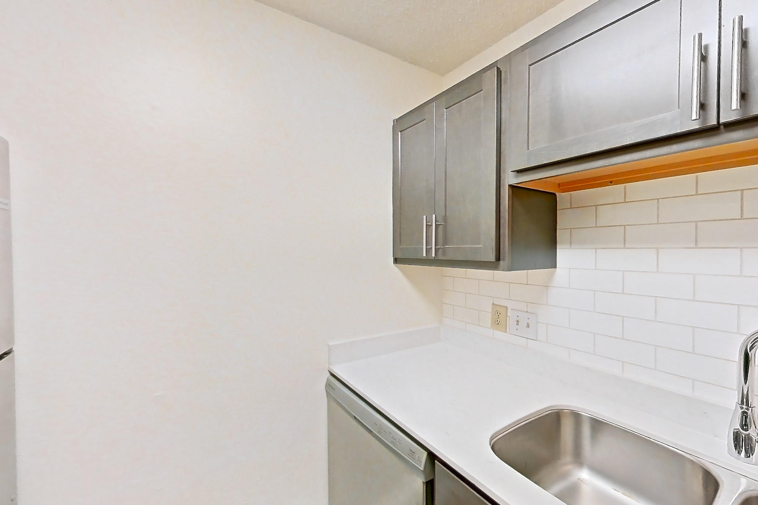 Kitchen with dishwasher, electric range, light countertops, light stone countertops, light wood-finish flooring, oven/range, refrigerator, stainless steel appliances, and white appliances, Apartment 15106 at The Boulders