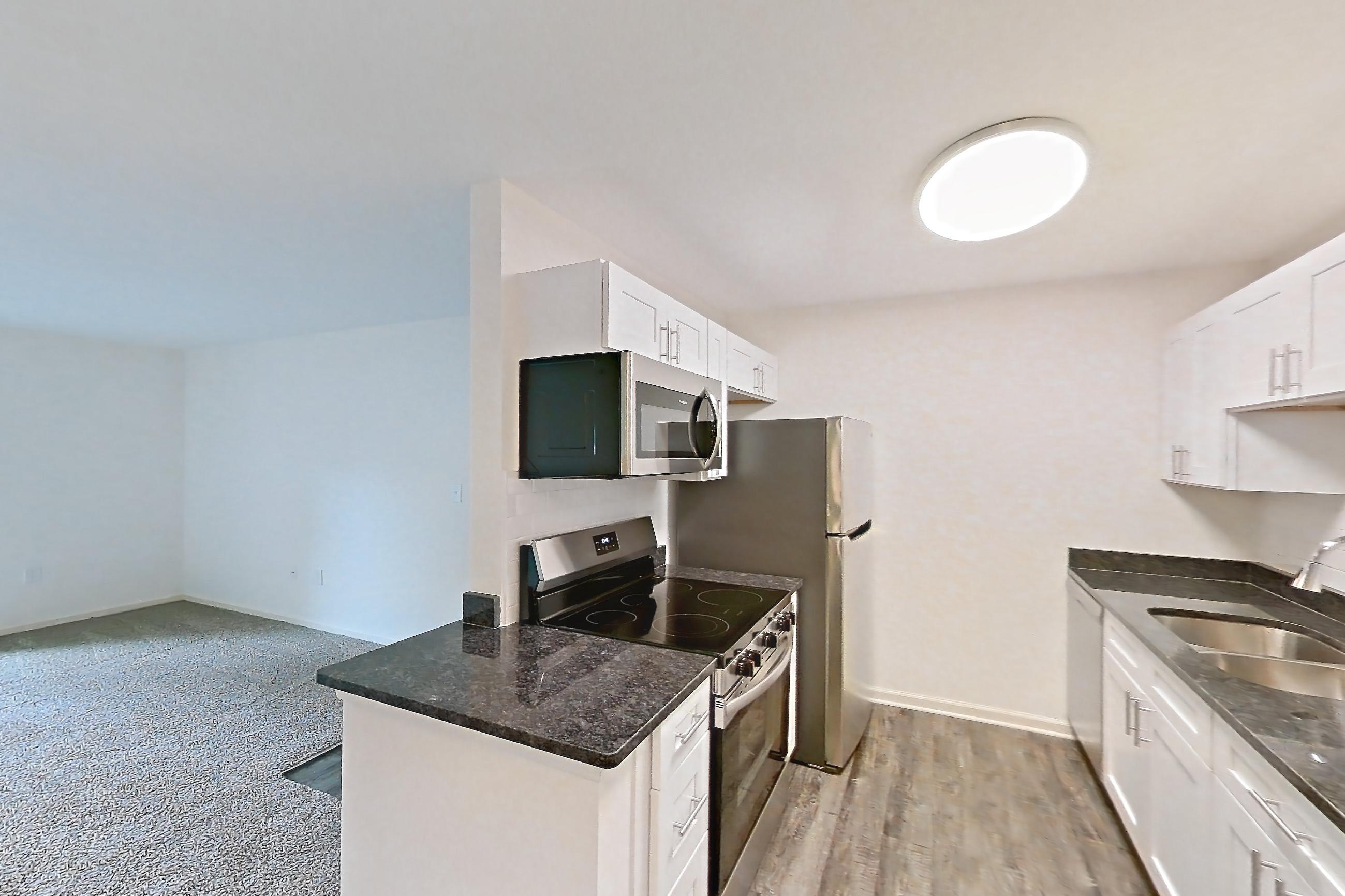 Dining room with dark carpet, dark stone countertops, dark wood-finish flooring, dishwasher, electric range, light countertops, oven/range, refrigerator, stainless steel appliances, and white appliances, Apartment 68108 at The Boulders