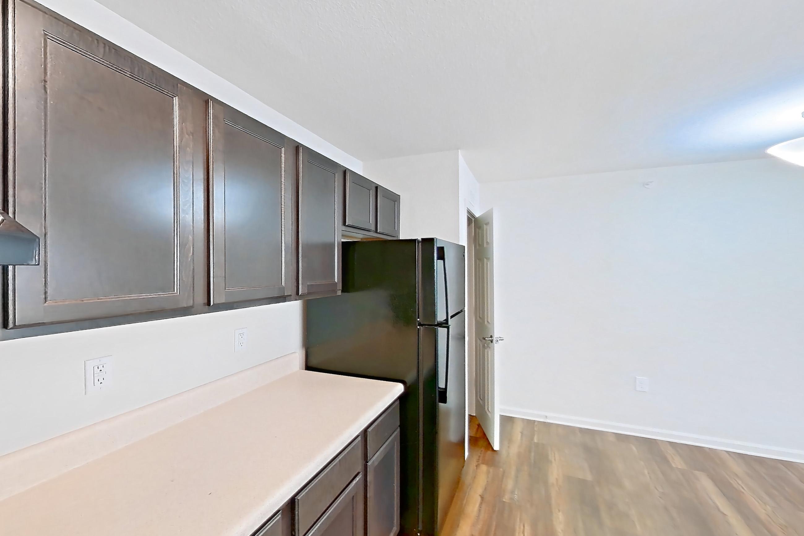 Kitchen with black appliances, dark wood-finish flooring, electric range, light countertops, light wood-finish flooring, oven/range, refrigerator, and stainless steel appliances, Apartment 8223 Unit 108 at The HUB on Harris