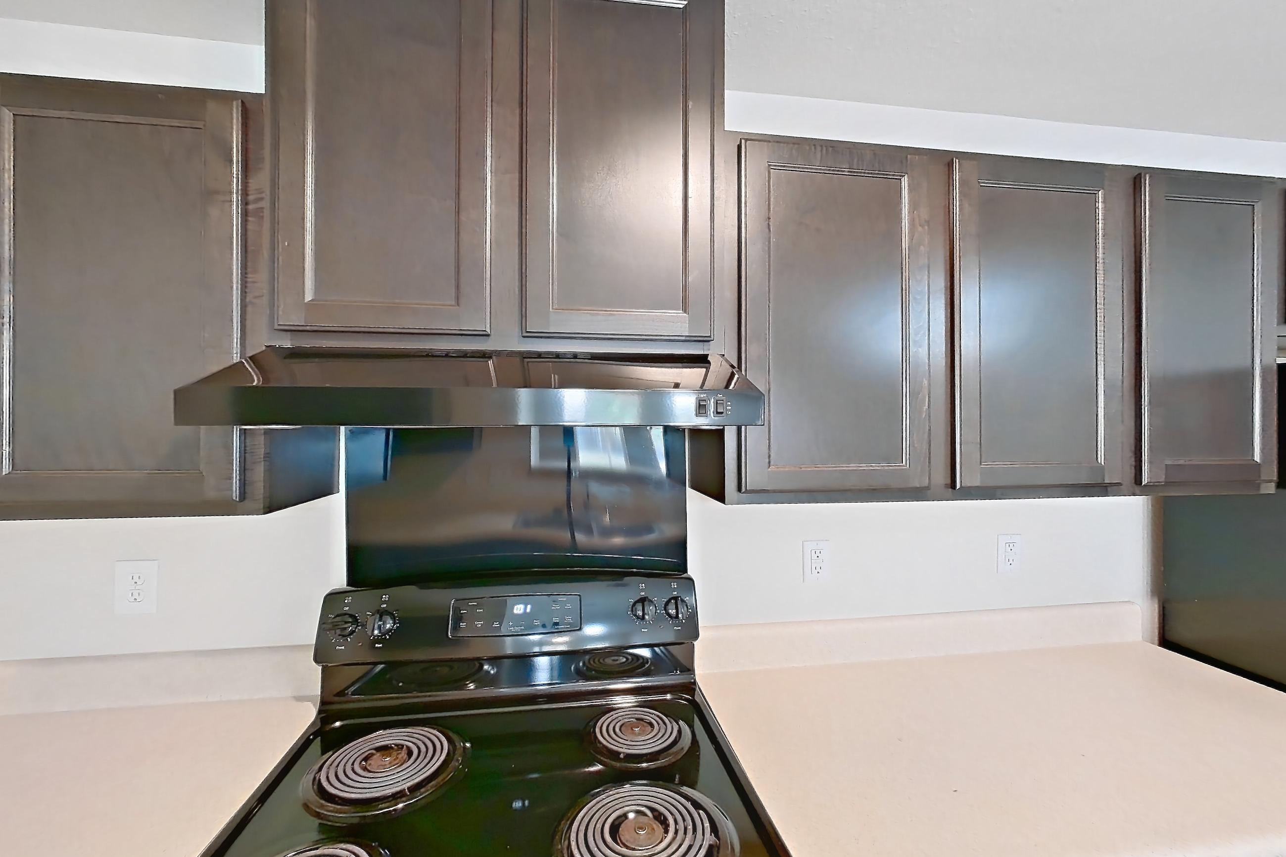 Kitchen with black appliances, dark wood-finish flooring, electric range, light countertops, light wood-finish flooring, oven/range, refrigerator, and stainless steel appliances, Apartment 8223 Unit 108 at The HUB on Harris