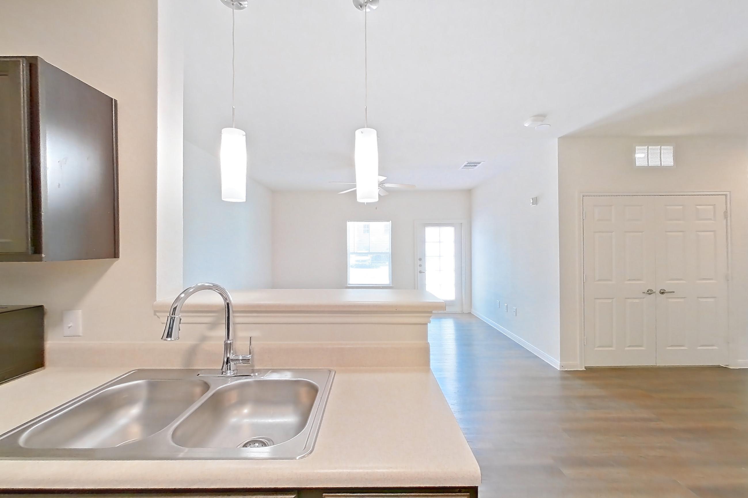 Kitchen with black appliances, dark wood-finish flooring, dishwasher, light countertops, light wood-finish flooring, microwave, oven/range, refrigerator, and stainless steel appliances, Apartment 11105 at Canyon Pass