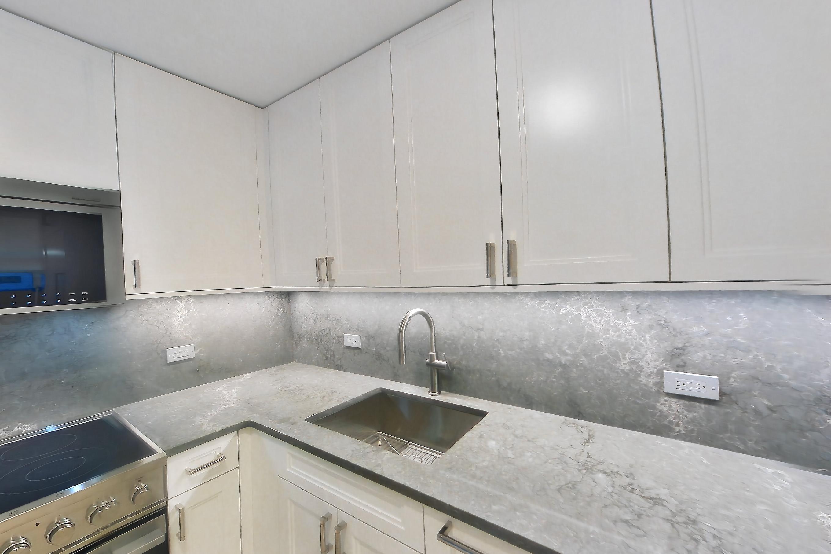 Kitchen with dark countertops, electric range, light stone countertops, light wood-finish flooring, microwave, oven/range, and stainless steel appliances, Apartment 1C at Stonehenge Leasing