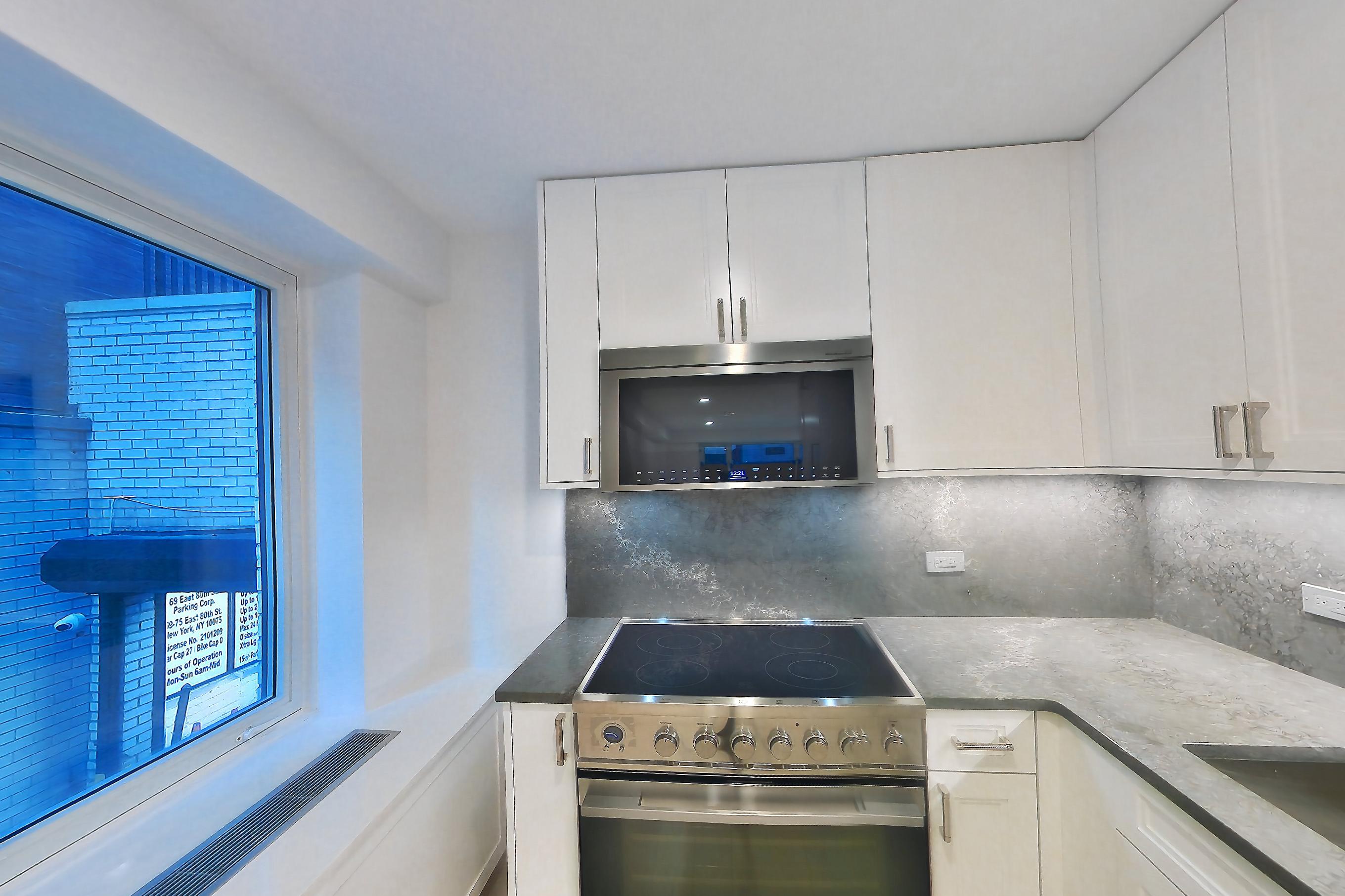 Kitchen with dark countertops, electric range, light stone countertops, light wood-finish flooring, microwave, oven/range, and stainless steel appliances, Apartment 1C at Stonehenge Leasing