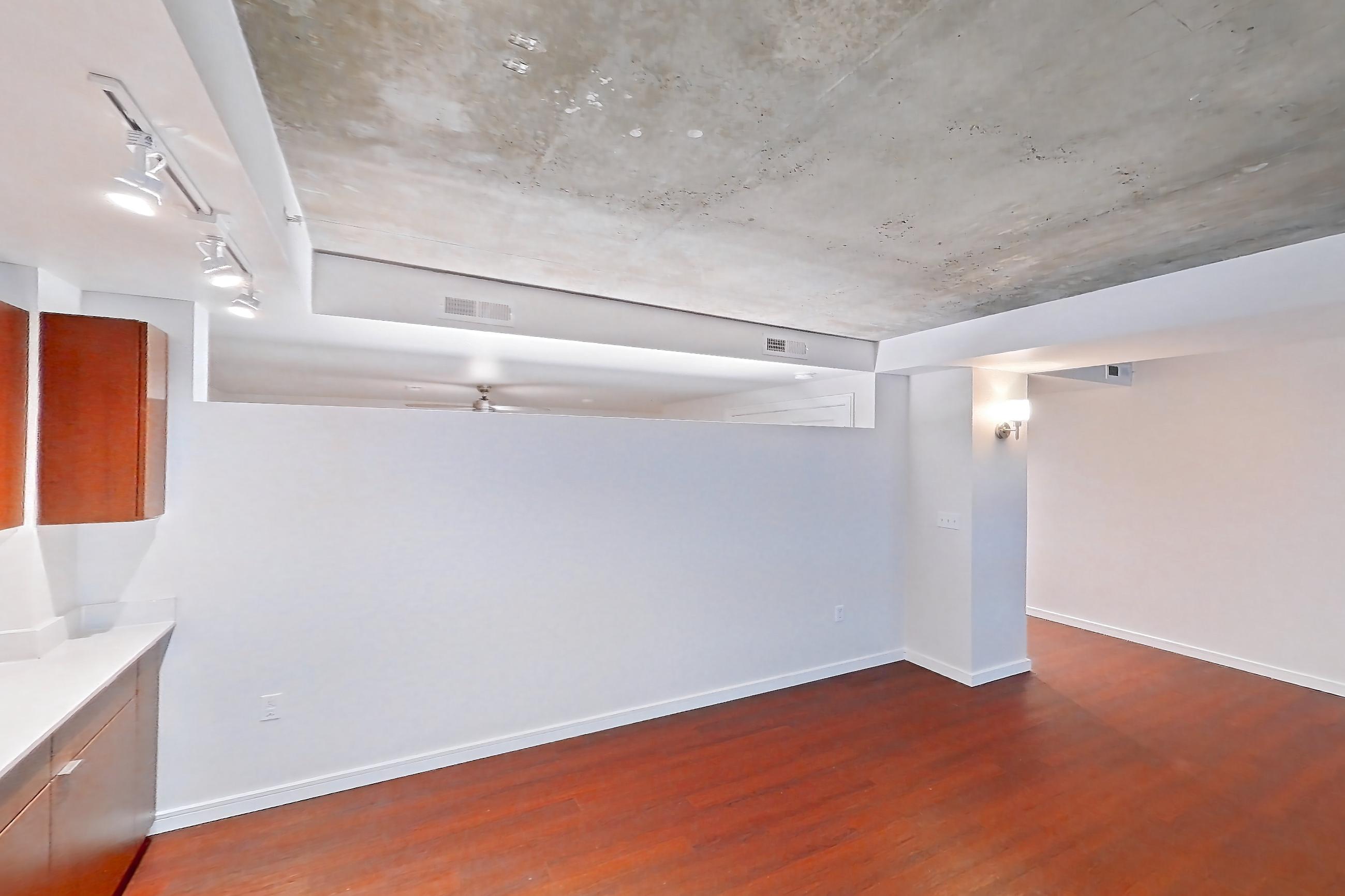 Kitchen with black appliances, dark wood-finish flooring, dishwasher, electric range, light countertops, light stone countertops, light wood-finish flooring, microwave, oven/range, refrigerator, and stainless steel appliances, Apartment 301 at Solera