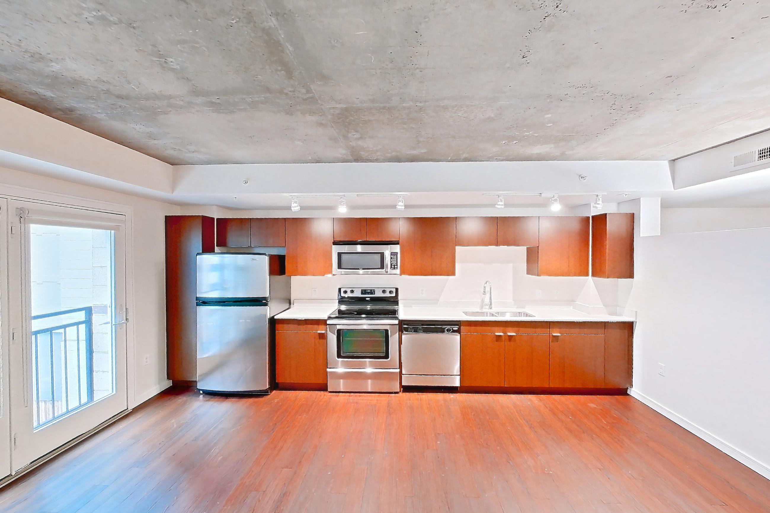Living space with dark wood-finish flooring, dishwasher, electric range, light countertops, oven/range, refrigerator, stainless steel appliances, and wood-finish flooring, Apartment 301 at Solera