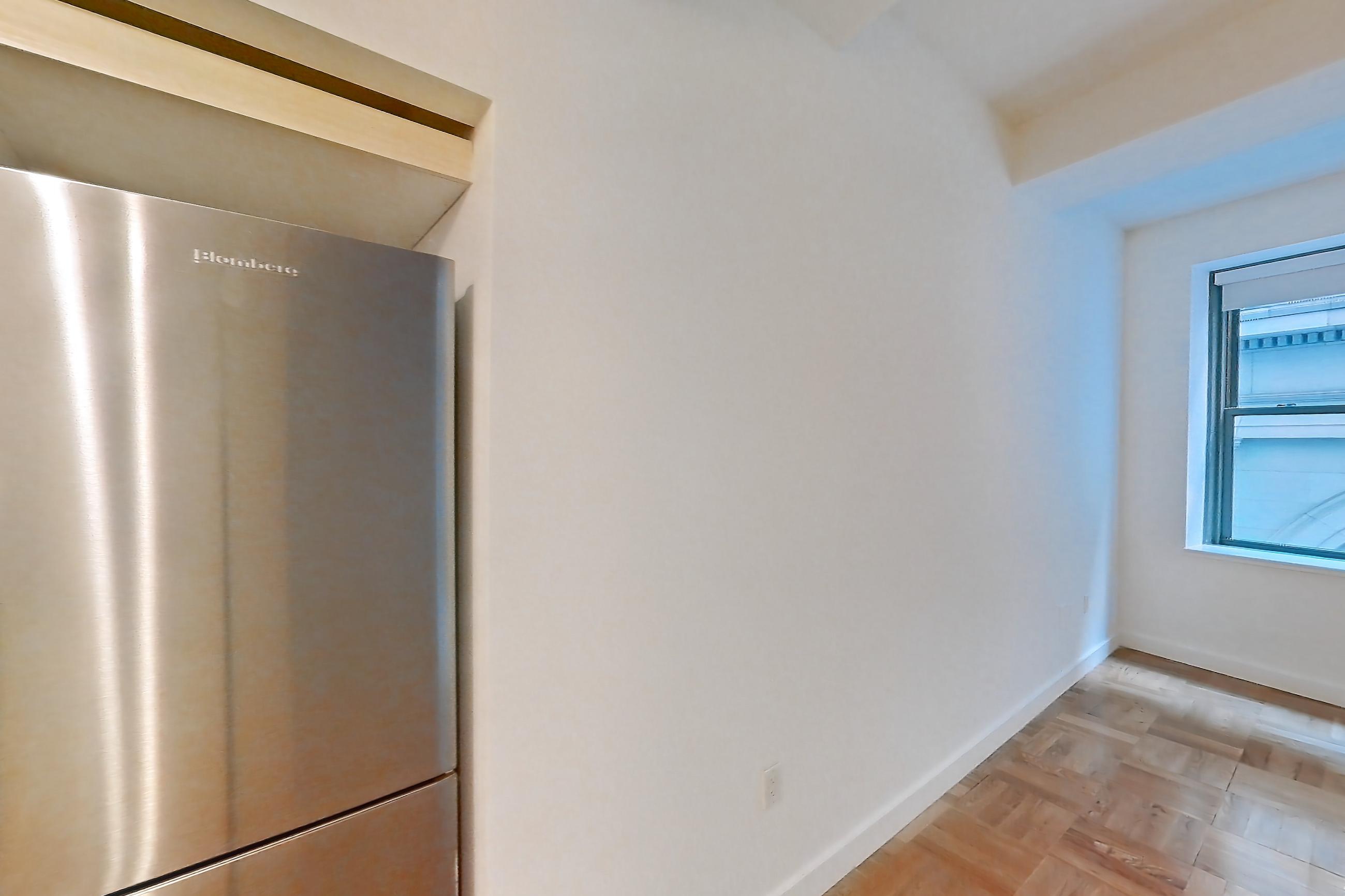 Kitchen with cooktop, dark stone countertops, gas cooktop, gas range, light countertops, light wood-finish flooring, microwave, oven/range, parquet flooring, refrigerator, and stainless steel appliances, Apartment 419 at 20 Exchange Place