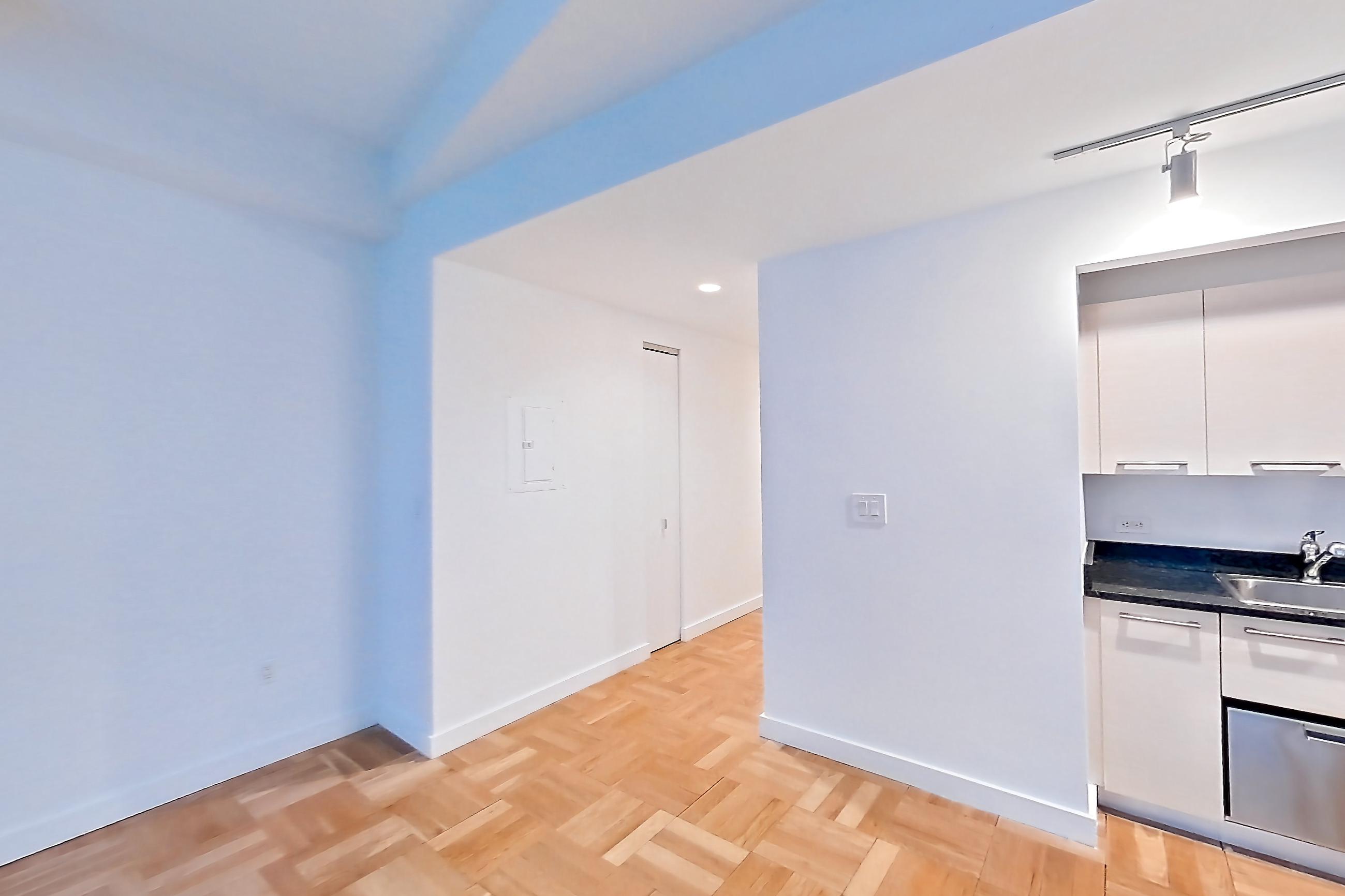 Living space with dark stone countertops, gas range, light countertops, light wood-finish flooring, microwave, oven/range, parquet flooring, refrigerator, and stainless steel appliances, Apartment 419 at 20 Exchange Place