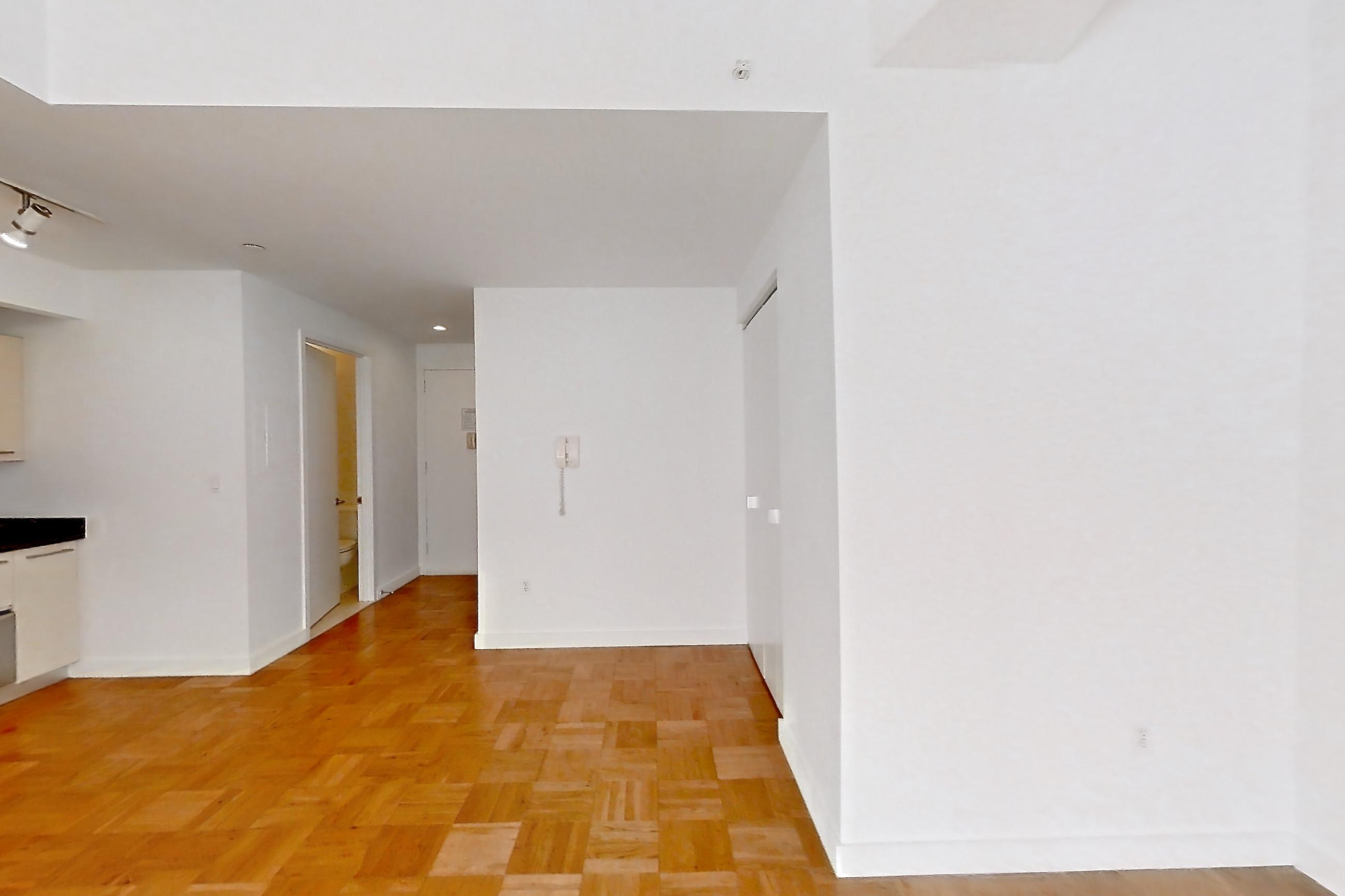 Living room with dark countertops, gas range, light wood-finish flooring, oven/range, parquet flooring, refrigerator, stainless steel appliances, and white appliances, Apartment 2104 at 20 Exchange Place