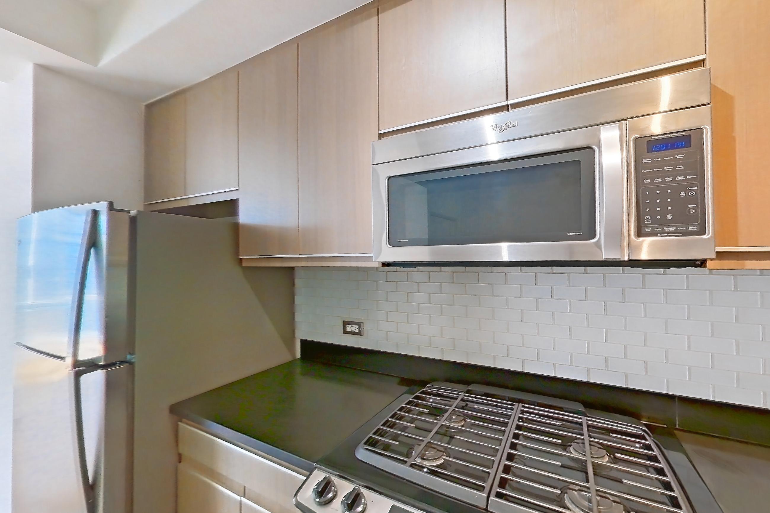 Kitchen with dark countertops, dishwasher, gas range, light countertops, light tile flooring, microwave, oven/range, refrigerator, stainless steel appliances, and white appliances, Apartment 24F at 66 Rockwell