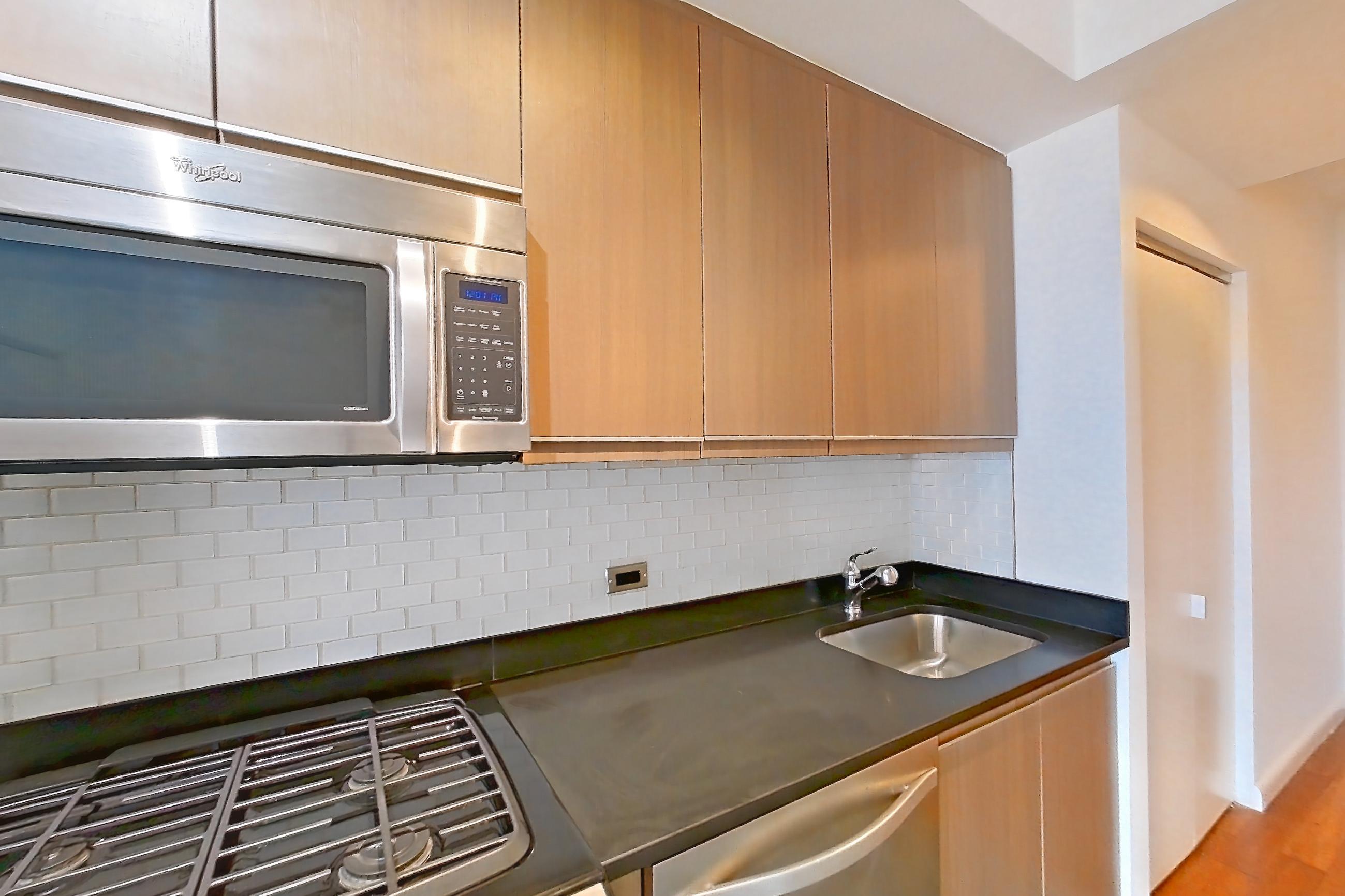 Kitchen with dark countertops, dishwasher, gas range, light countertops, light tile flooring, microwave, oven/range, refrigerator, stainless steel appliances, and white appliances, Apartment 24F at 66 Rockwell