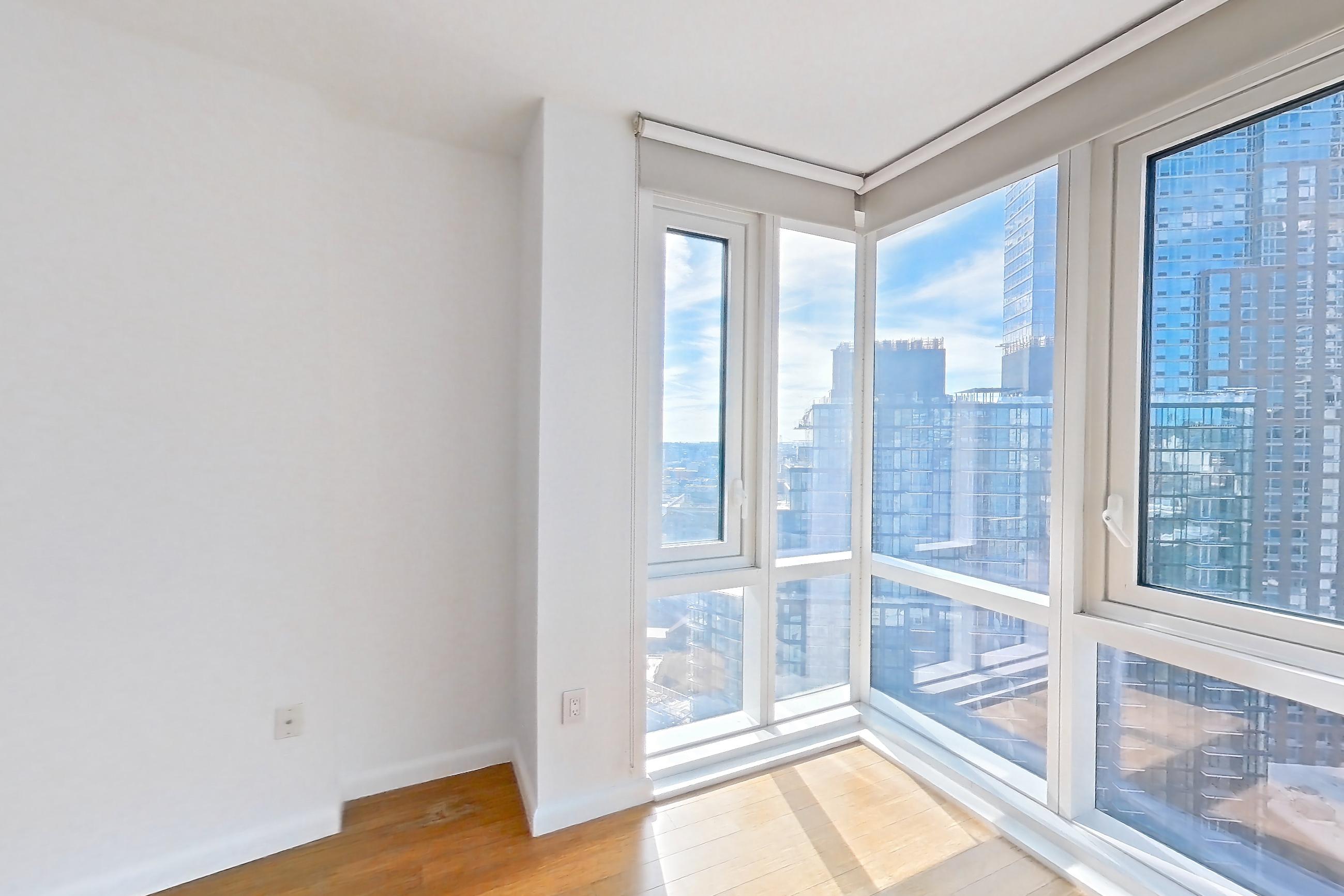 Living room with light wood-finish flooring and refrigerator, Apartment 24F at 66 Rockwell