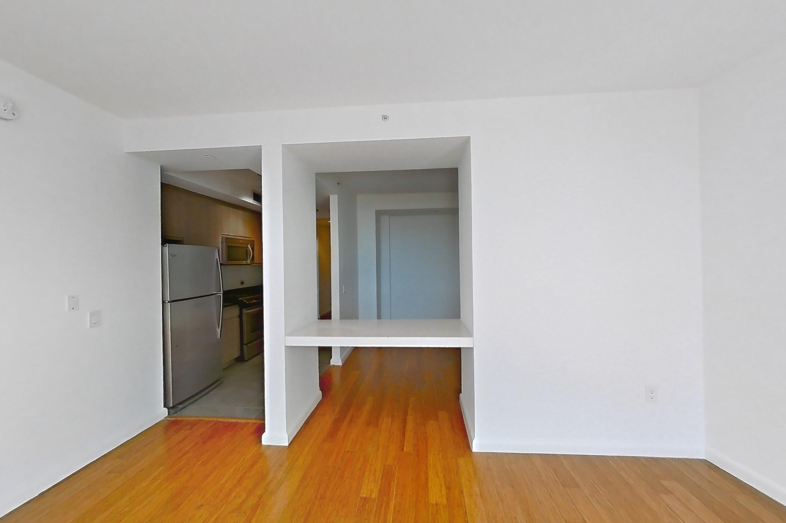 Living room with light wood-finish flooring and refrigerator, Apartment 24F at 66 Rockwell